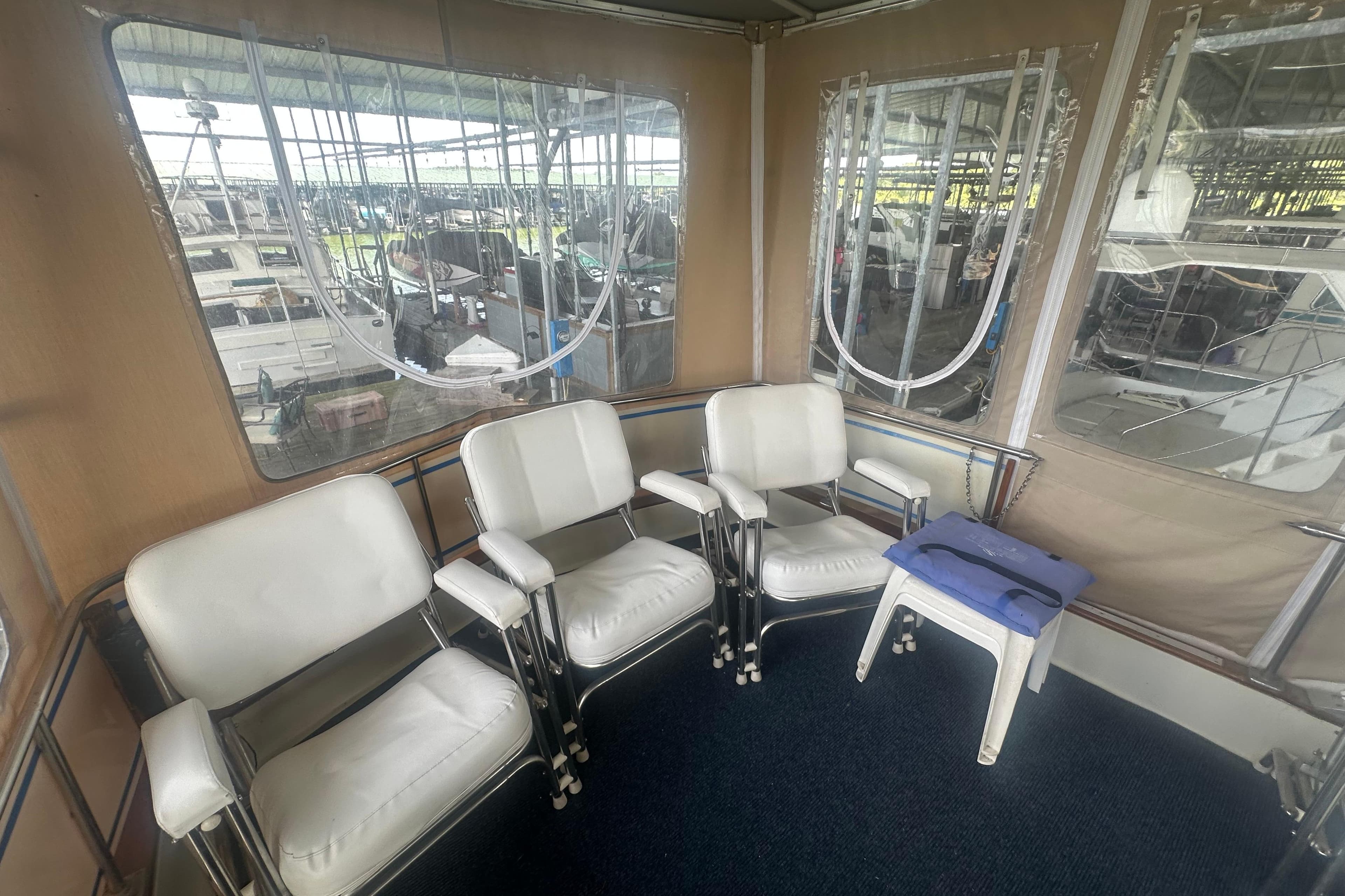 1971 Chris-Craft Commander 42 interior with white chairs and windows in a marina setting.
