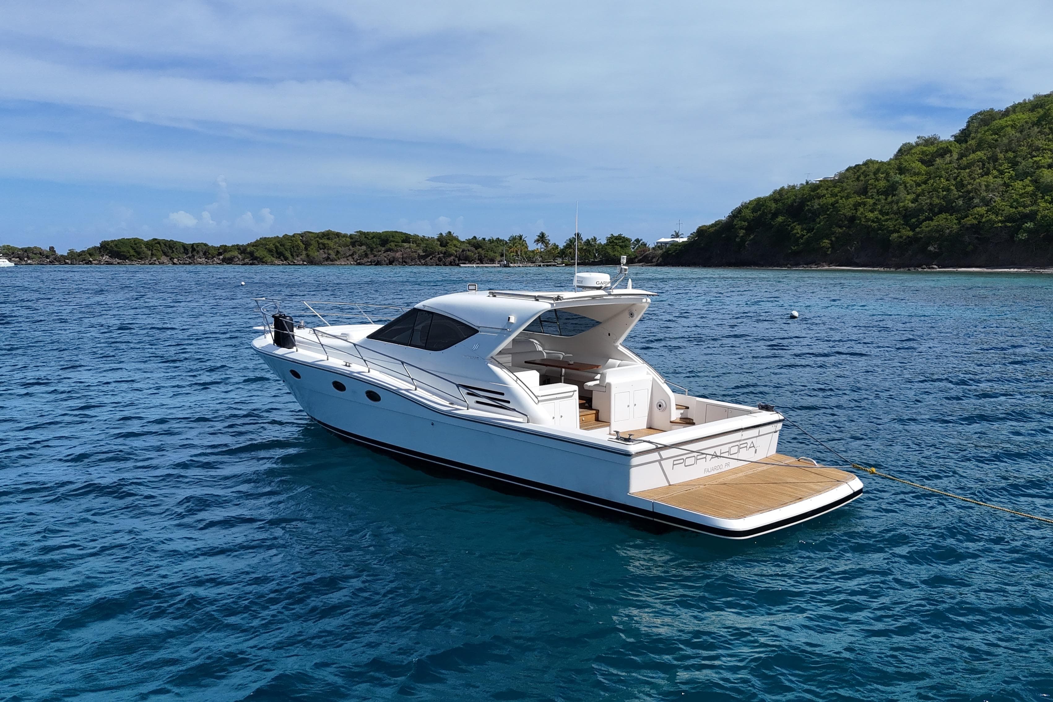 2013 Uniesse 49 yacht anchored in clear blue water near a lush green island.