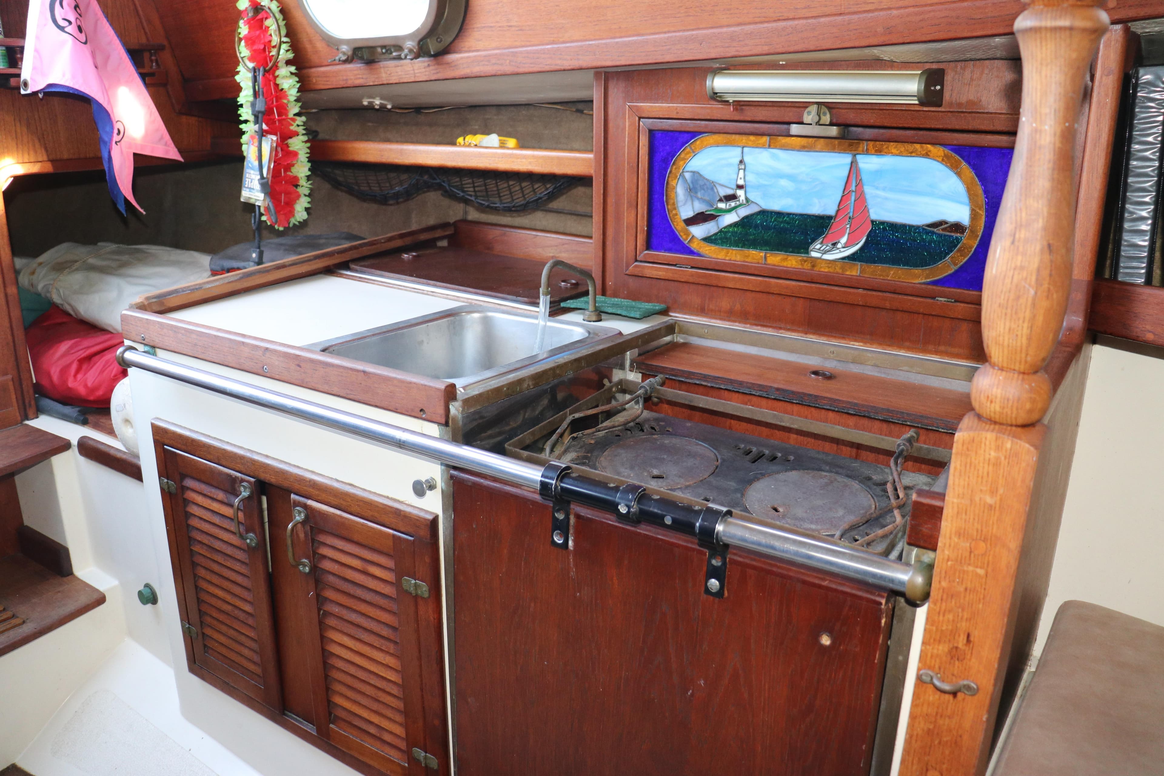 Interior of 1982 Pacific Seacraft Flicka 20 sailboat with wooden cabinetry and compact kitchen.