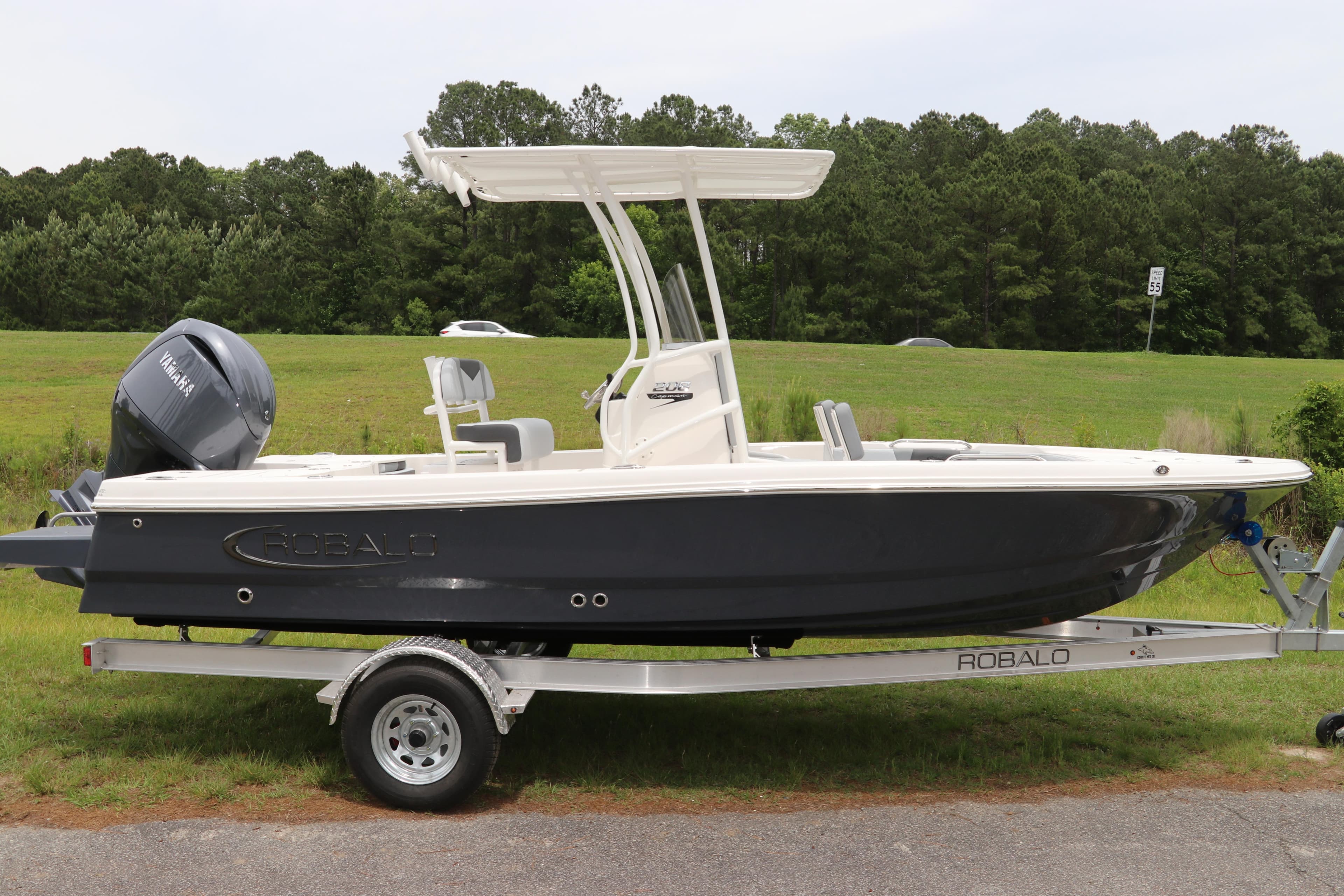 2026 Robalo 206 Cayman boat on trailer, parked outdoors with lush green background.