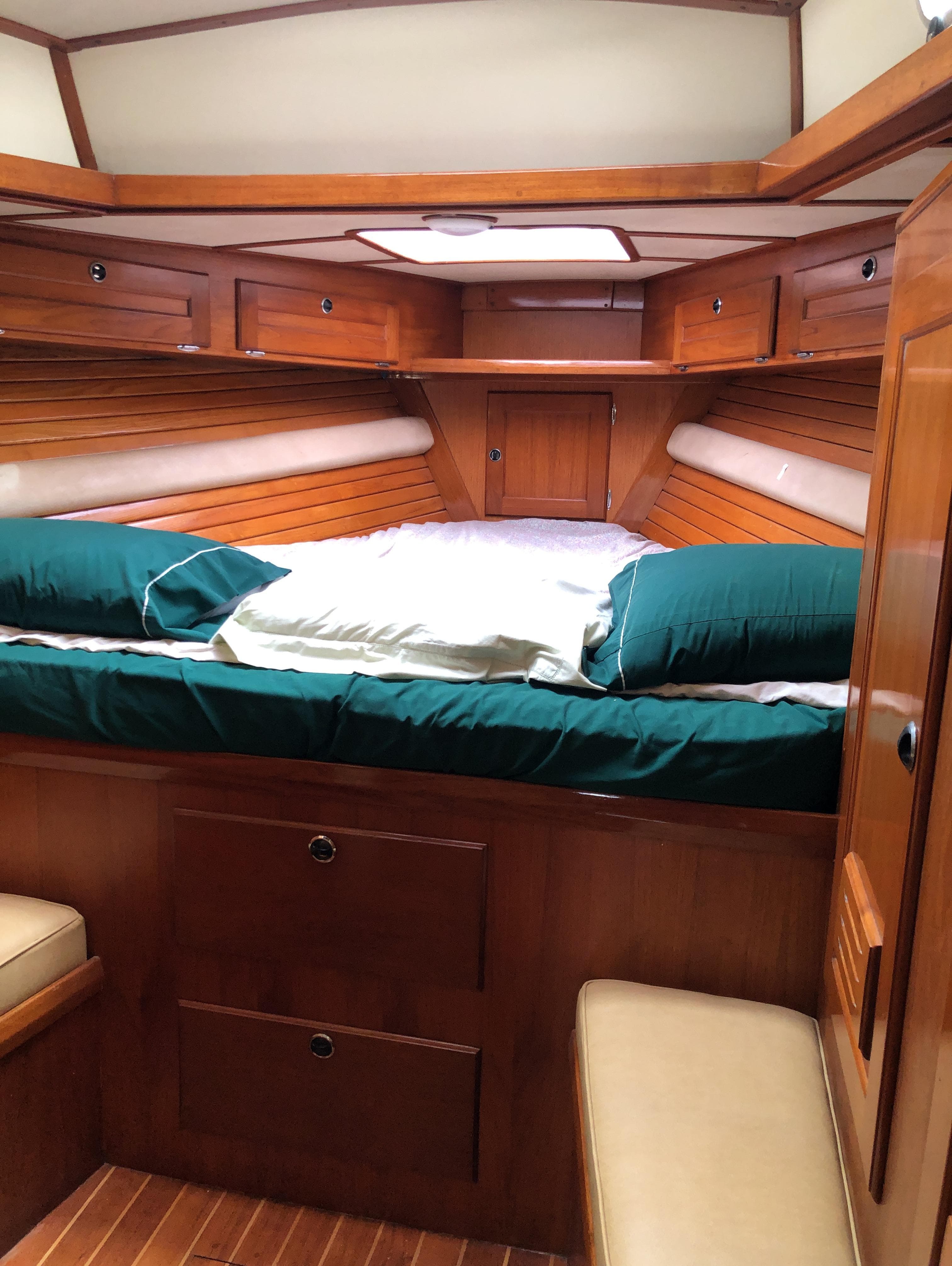 Cozy cabin interior of 1995 Valiant 50 yacht with wooden finish and green bedding.