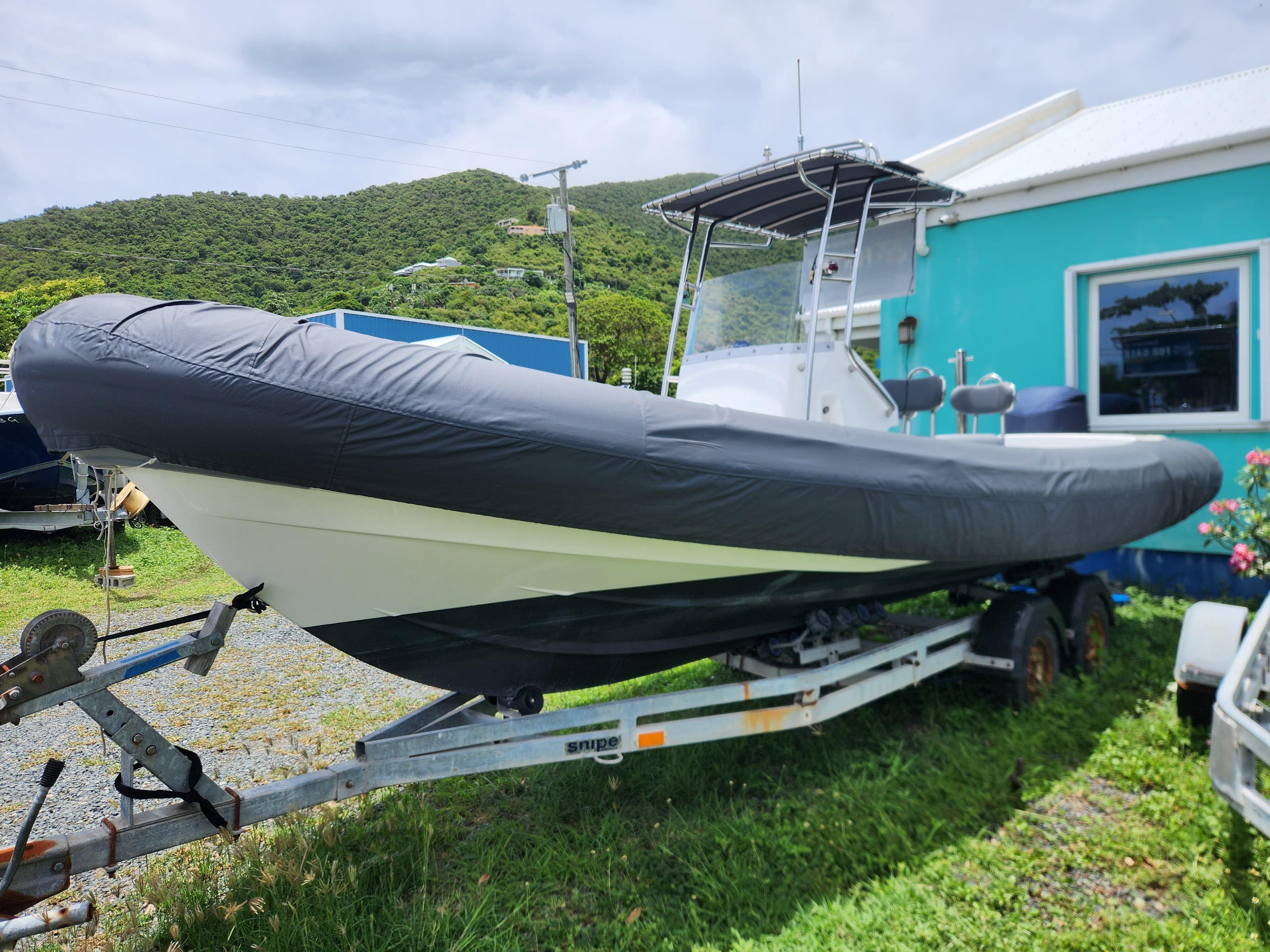2023 Island RIBs 7.5 m boat on trailer, parked beside a turquoise building.