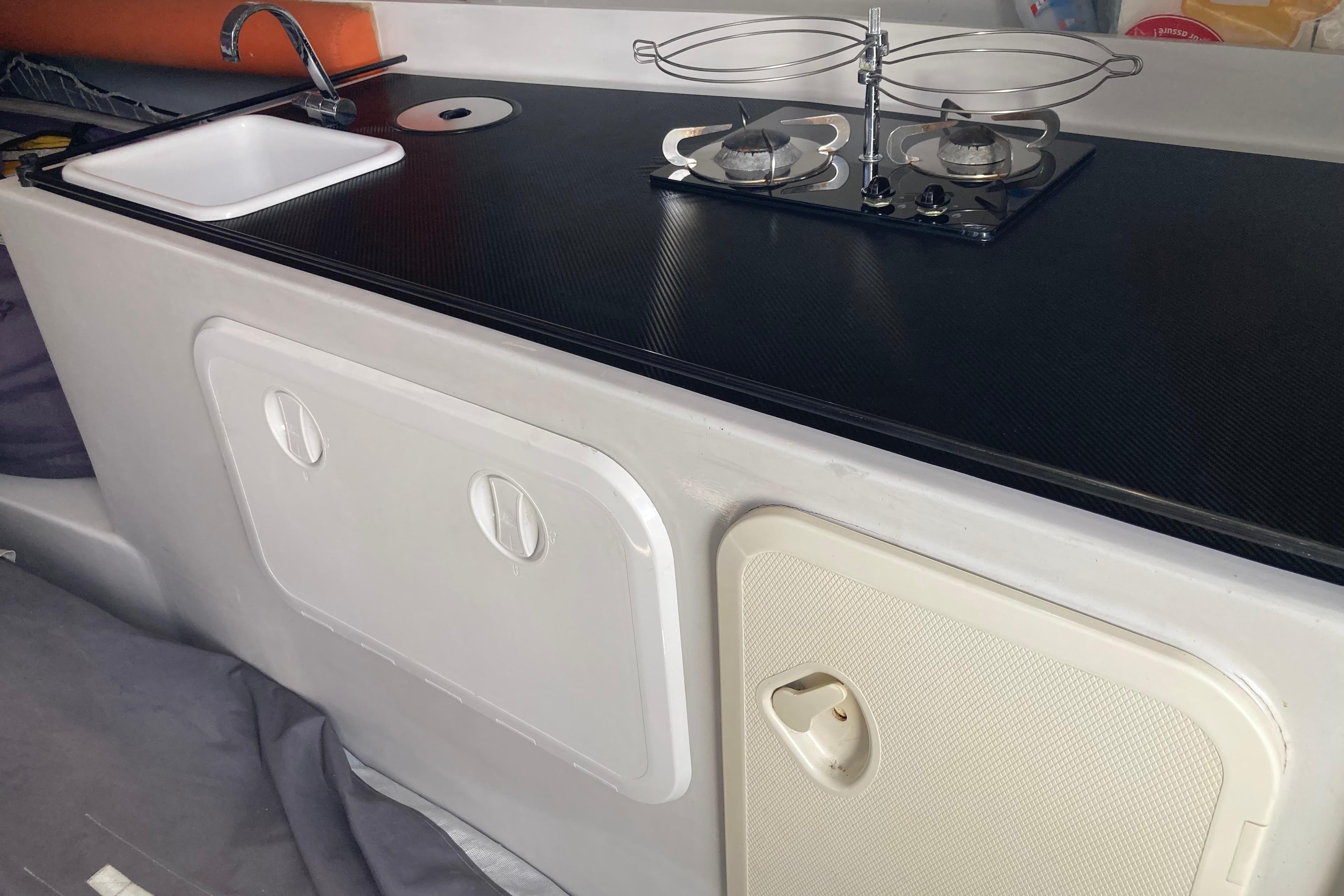 Compact kitchen setup in a 2014 Black Pepper CODE 1 boat, featuring sink and stove.