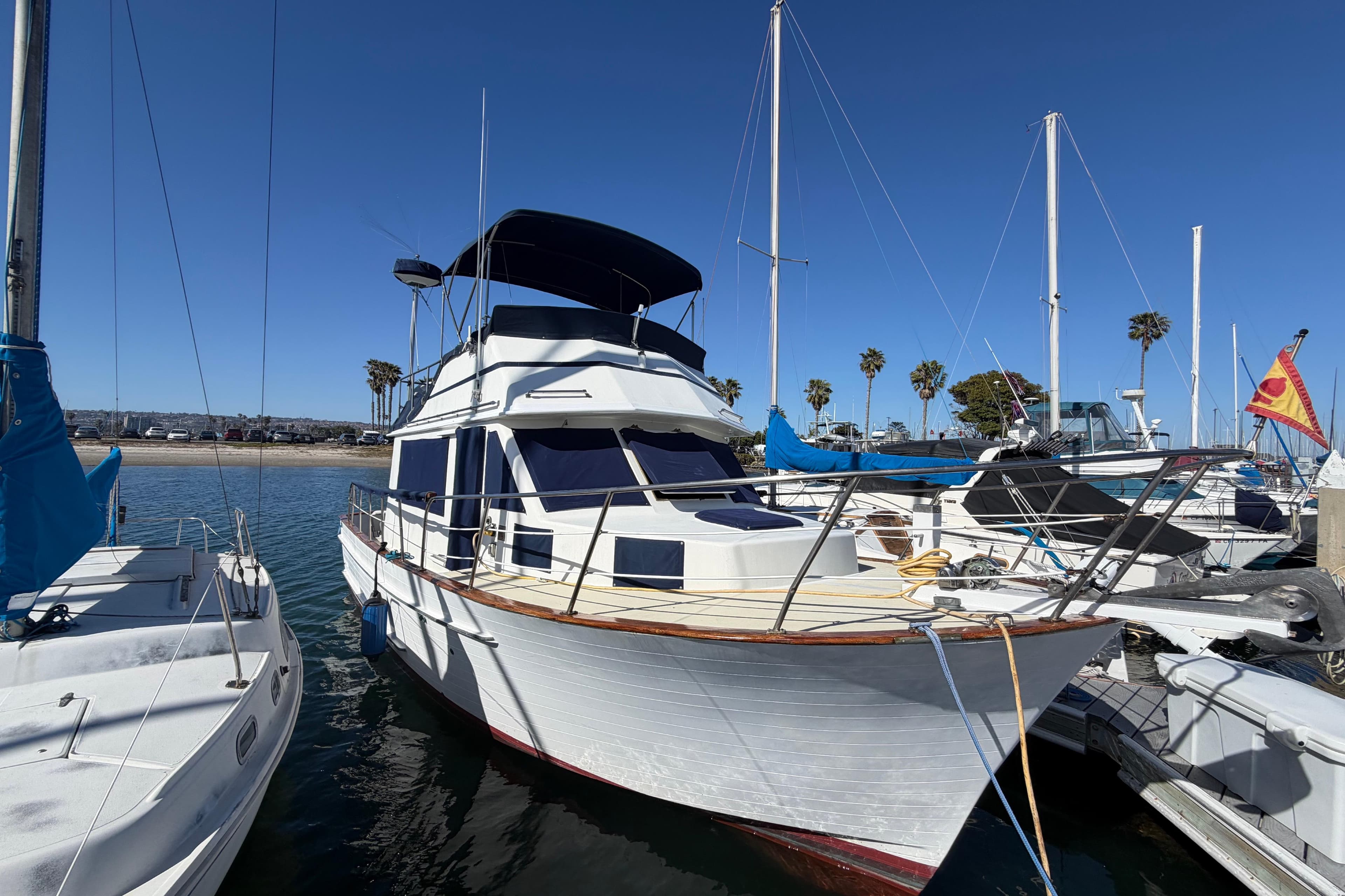 1982 Lien Hwa 31 yacht docked at marina, clear blue sky, palm trees in background.