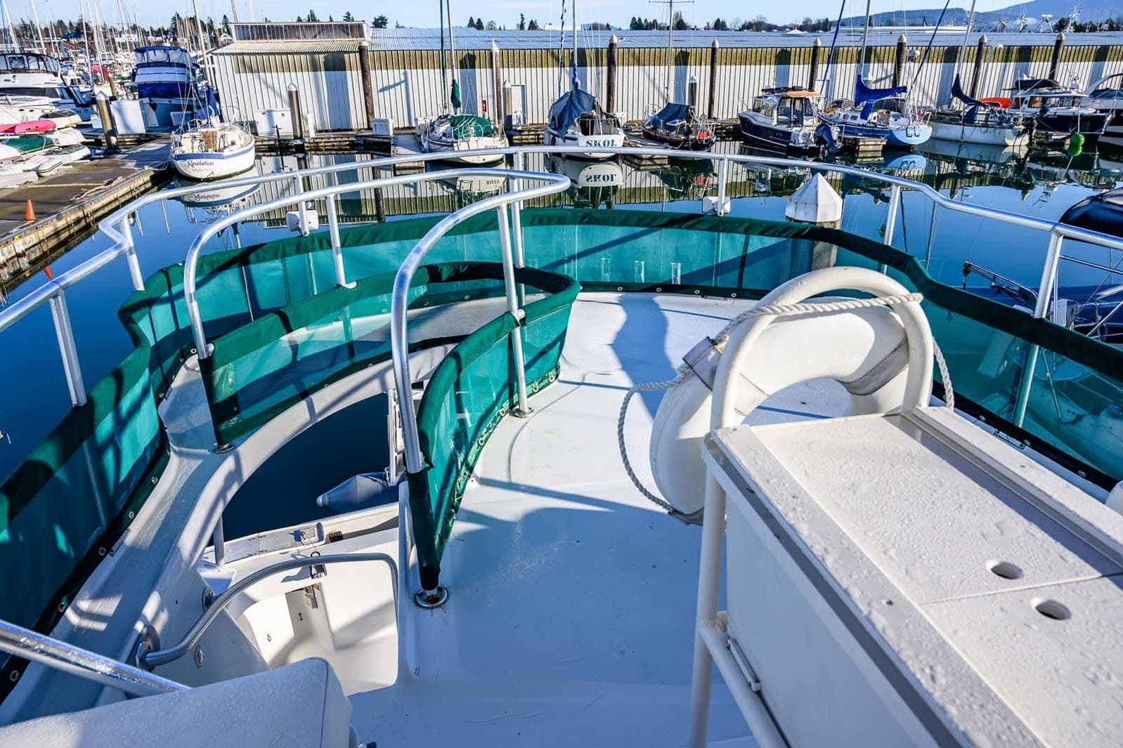 1997 Mainship 350 Trawler deck view at marina, featuring green railings and seating.