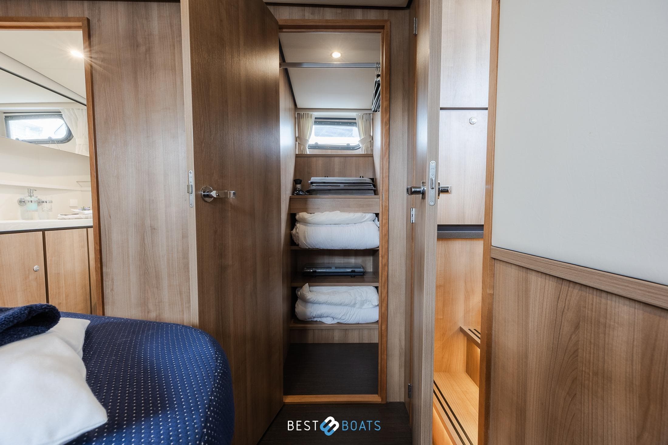 Interior of 2022 Linssen 40 SL AC yacht with wooden cabinetry and cozy bedding.
