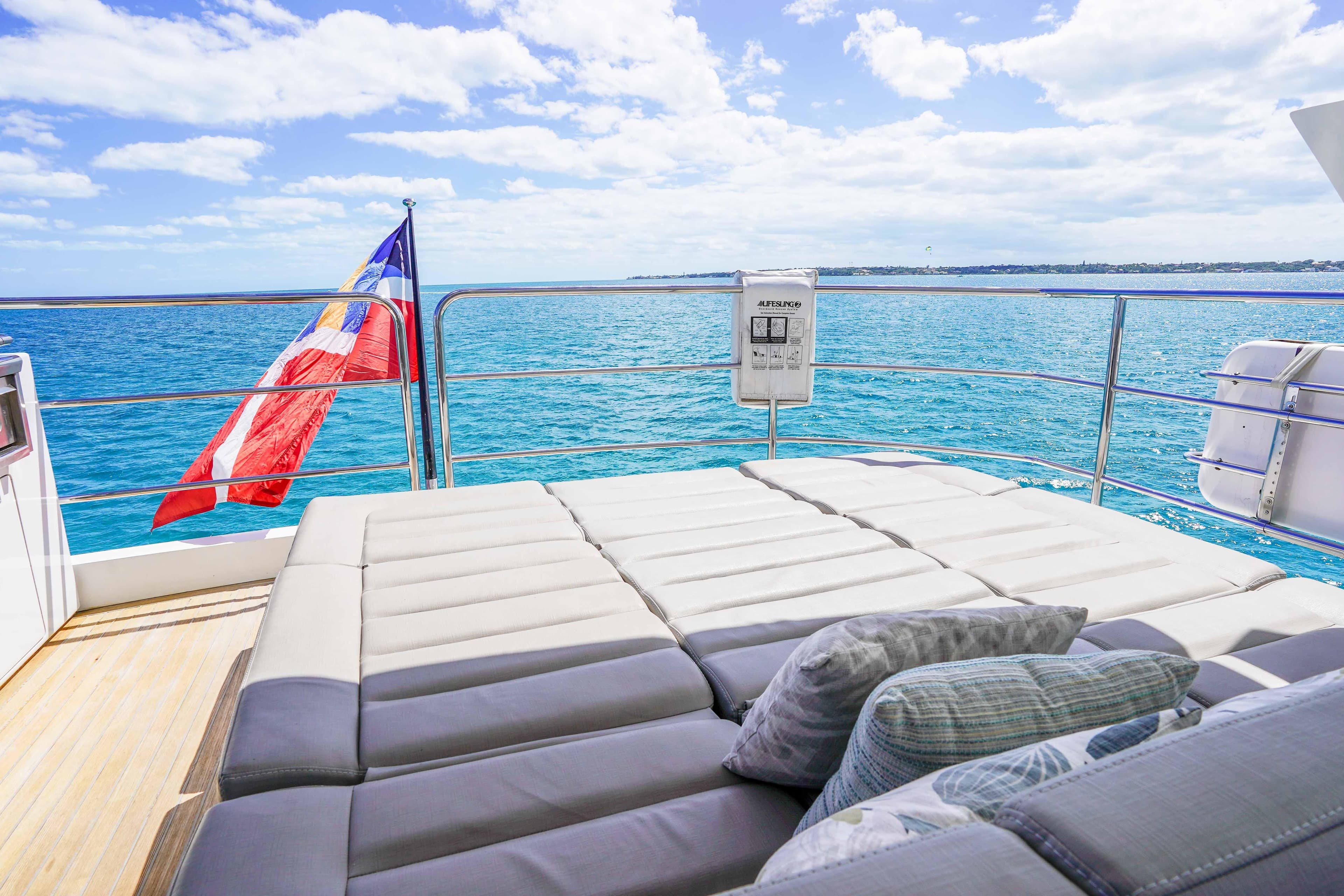 Luxurious Sunseeker 75 Yacht 2016 with sunbed, ocean view, and flag waving in the breeze.