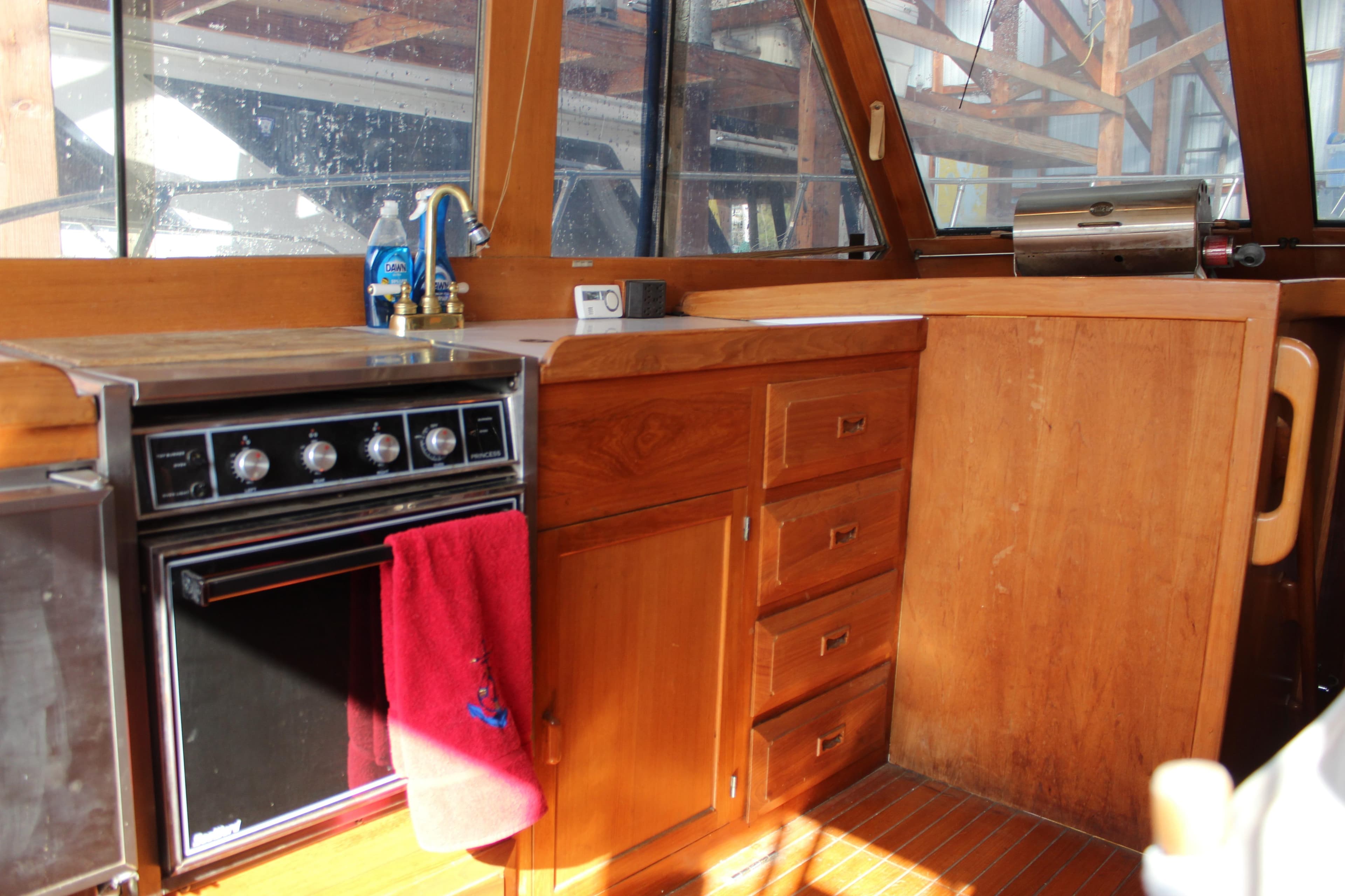 Interior of 1985 Ventura South Bay Flybridge Sedan Sport with wooden cabinetry and stove.