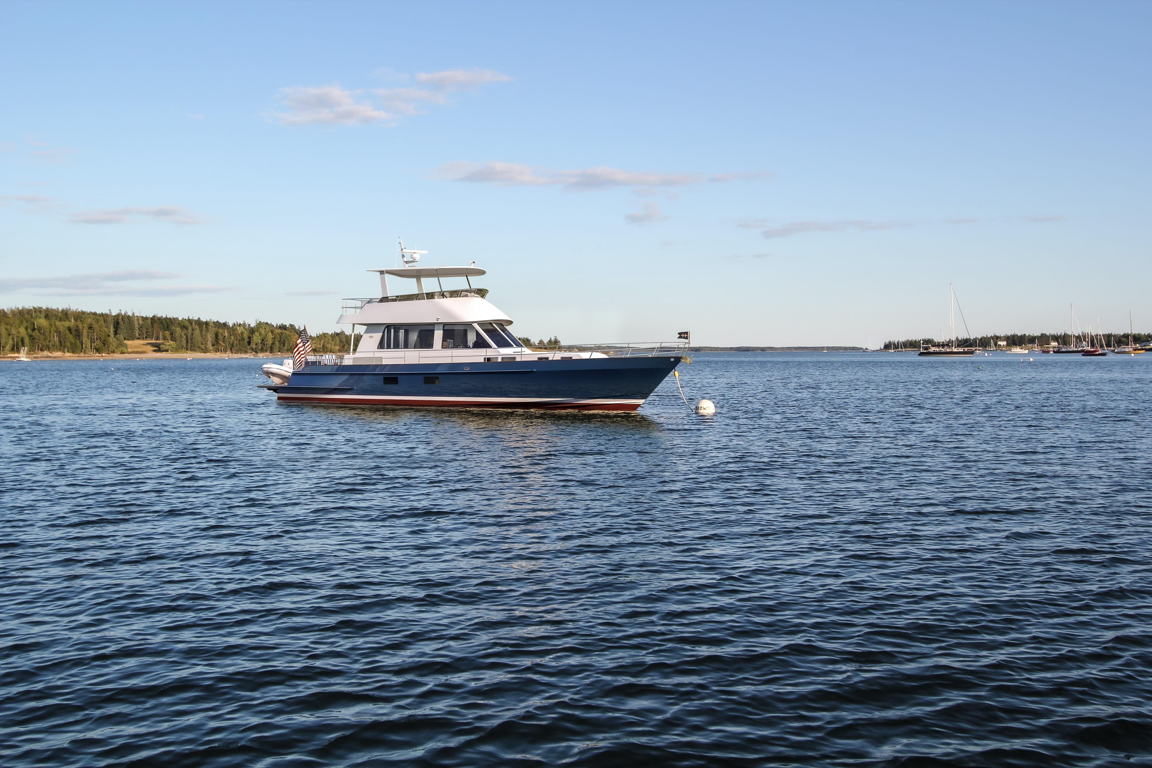 2027 Hunt Yachts 56 Ocean Flybridge on serene water with clear sky backdrop.