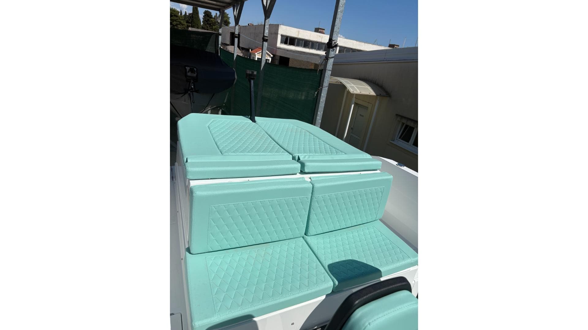 2025 De Antonio Yachts e23 open with turquoise seating, docked outdoors.