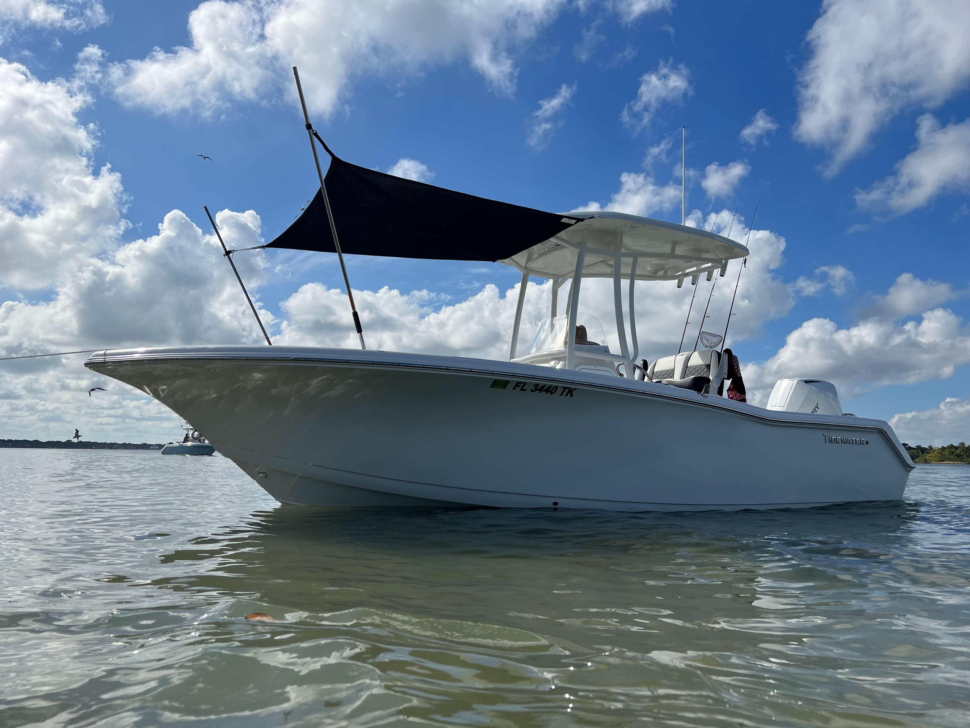 2023 Tidewater 220 CC Adventure boat on calm water under a blue sky.