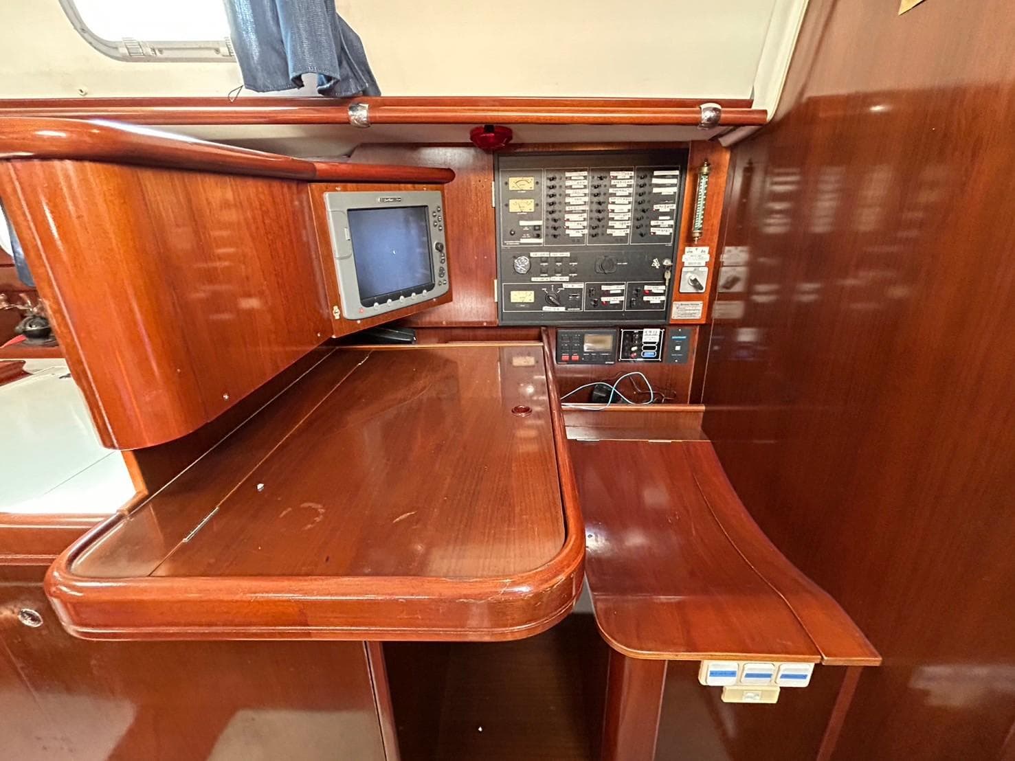 Navigation station of 1997 Beneteau Oceanis 50 with control panel and wooden finish.