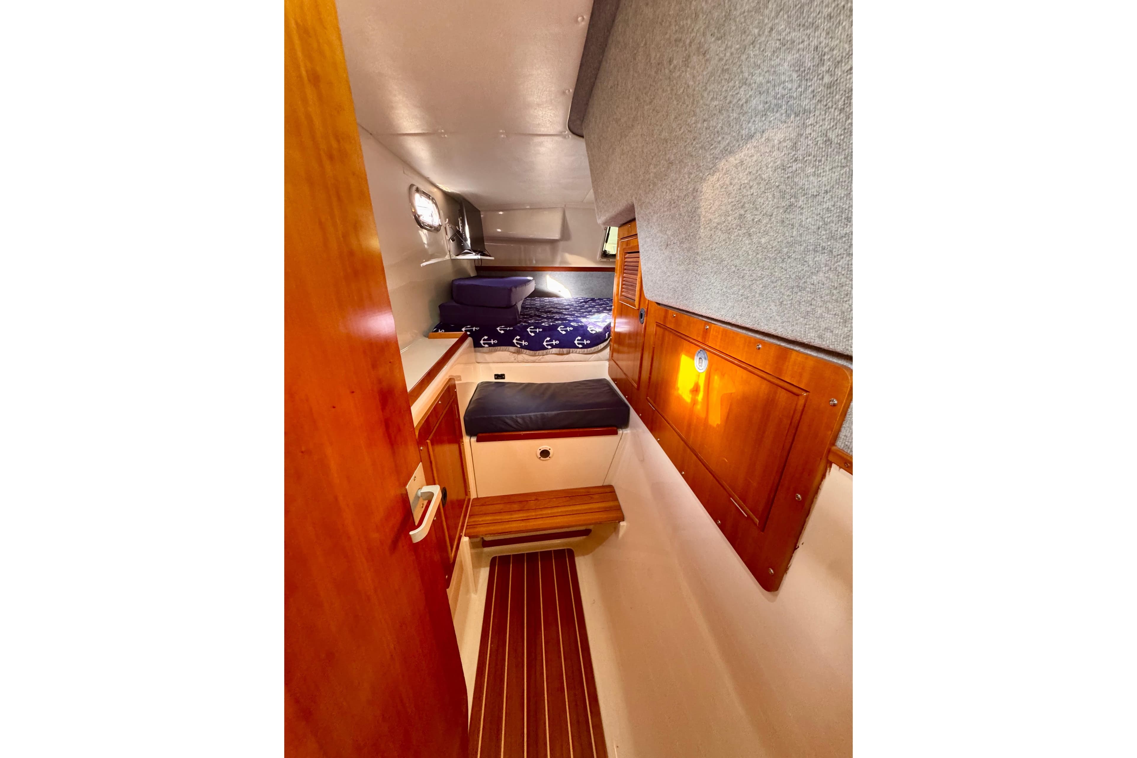 Interior cabin of 2006 PDQ PowerCat with wooden accents and cozy bedding.