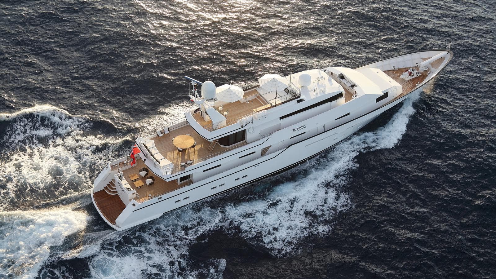 Luxurious 1982 Feadship Custom yacht cruising on open sea, aerial view.