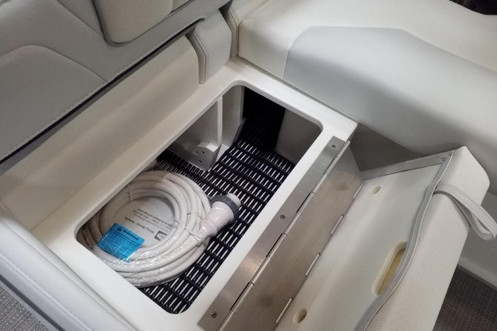 2020 Formula 310 Bowrider OB storage compartment with coiled hose inside.