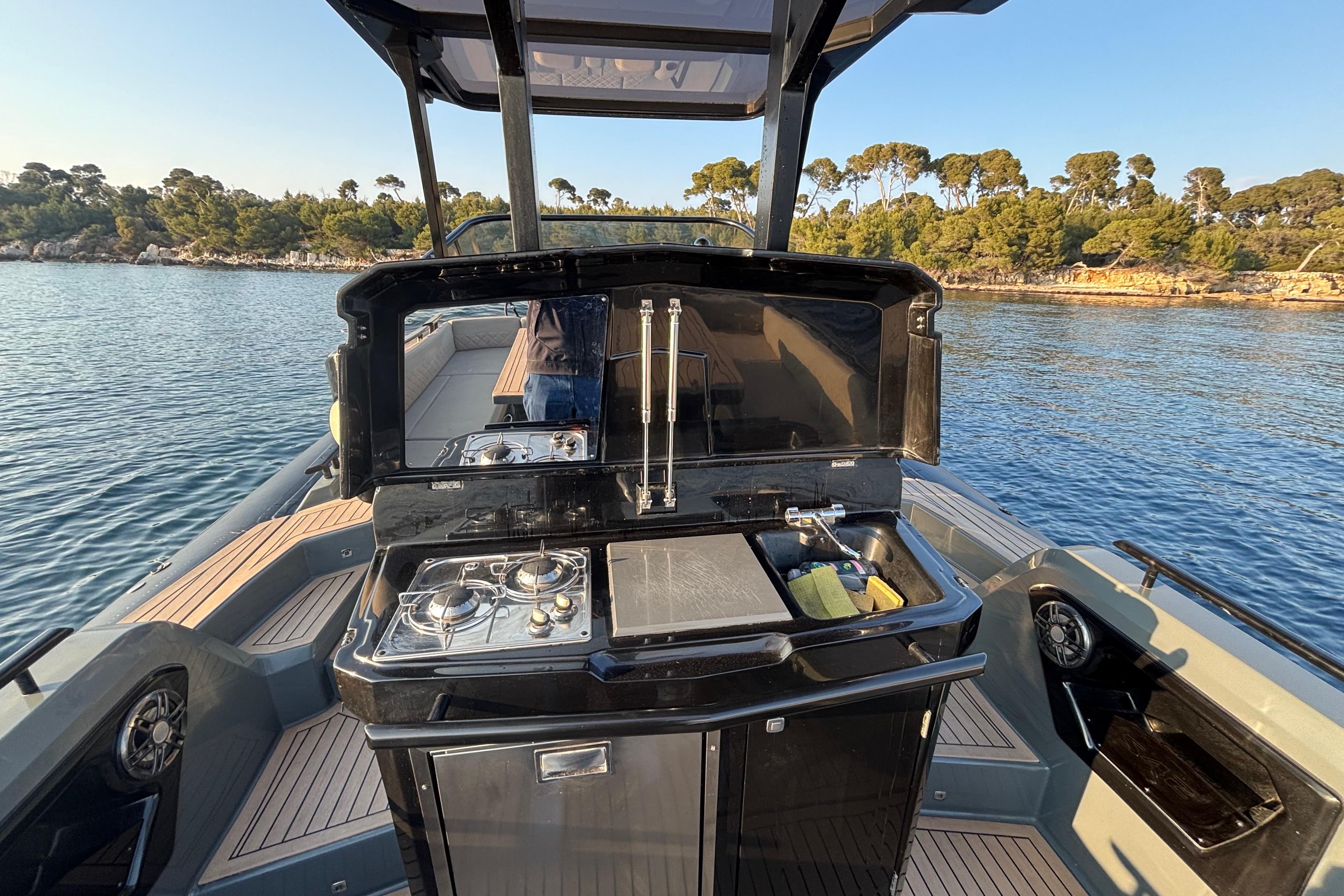 Outdoor kitchen on 2021 Salpa SOLEIL 42 boat, featuring stove and sink, with scenic water view.