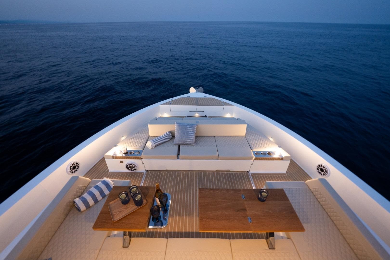 Luxurious 2026 De Antonio Yachts D60 deck at sunset, featuring elegant seating and tables.