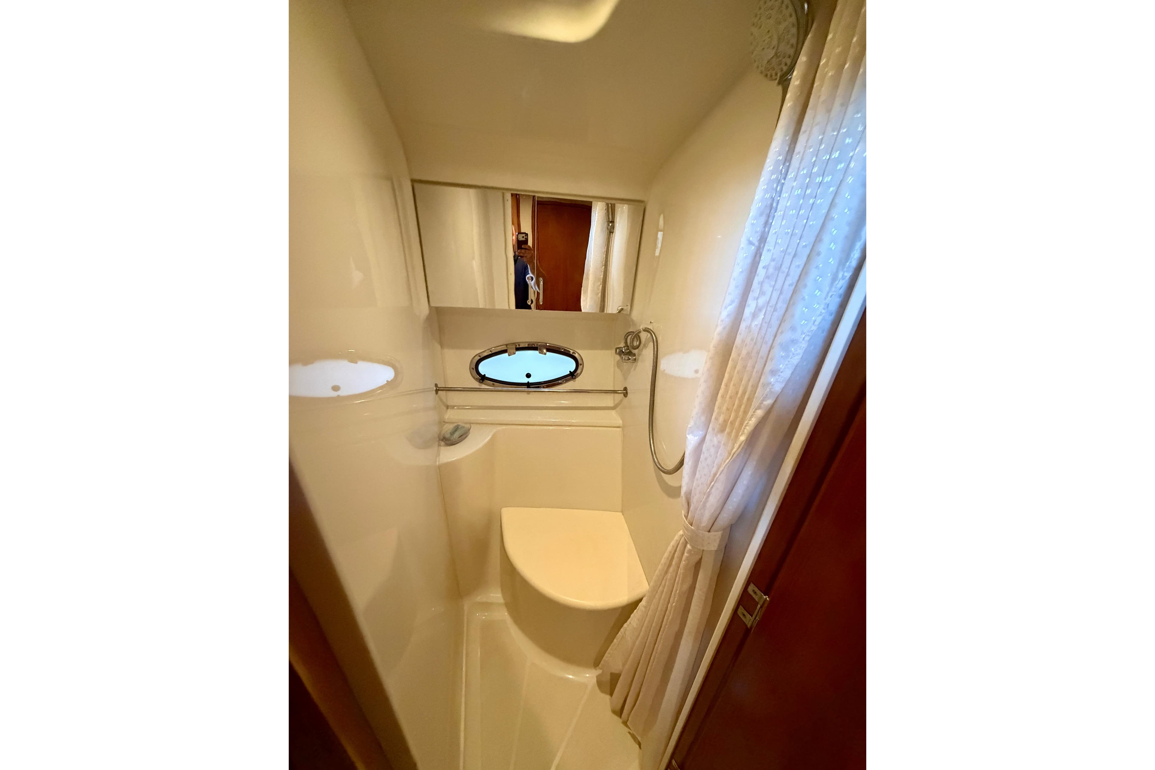 Bathroom interior of 2000 Carver 396 Motor Yacht with shower and porthole window.