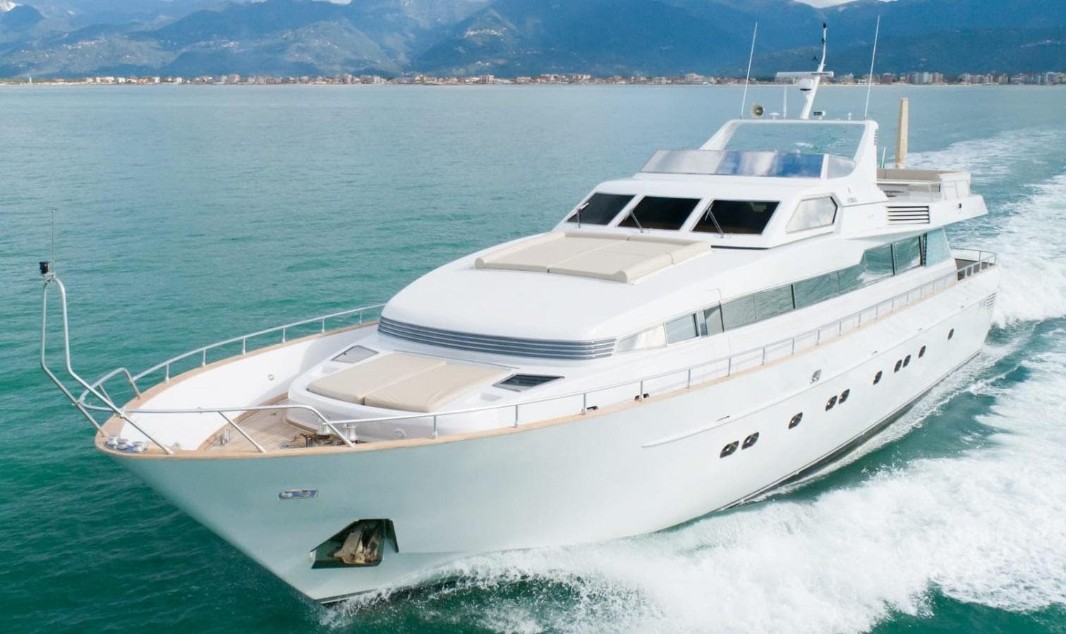 Luxurious 1992 Admiral 28 yacht cruising on open water with scenic mountain backdrop.