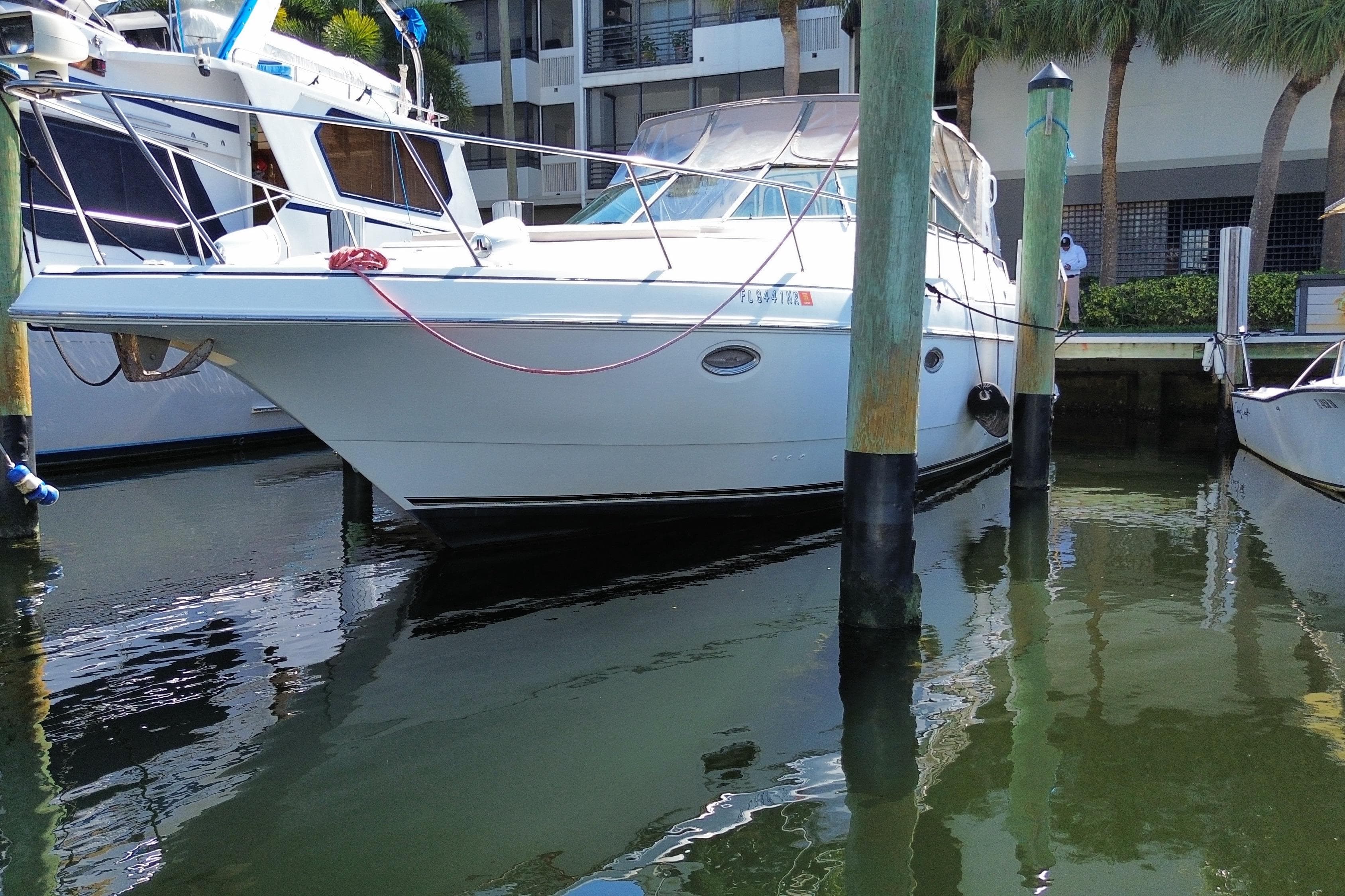 2002 Cruisers Yachts 3572 Express docked at marina, reflecting on calm water.