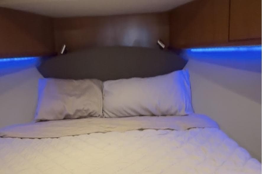 Luxurious bedroom interior of 2008 Luhrs 36 Convertible yacht with ambient blue lighting.