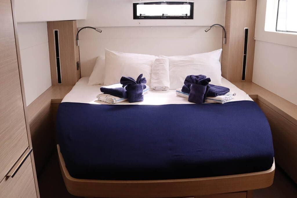 Luxurious cabin interior of 2023 Lagoon 46 yacht with neatly arranged bed and towels.