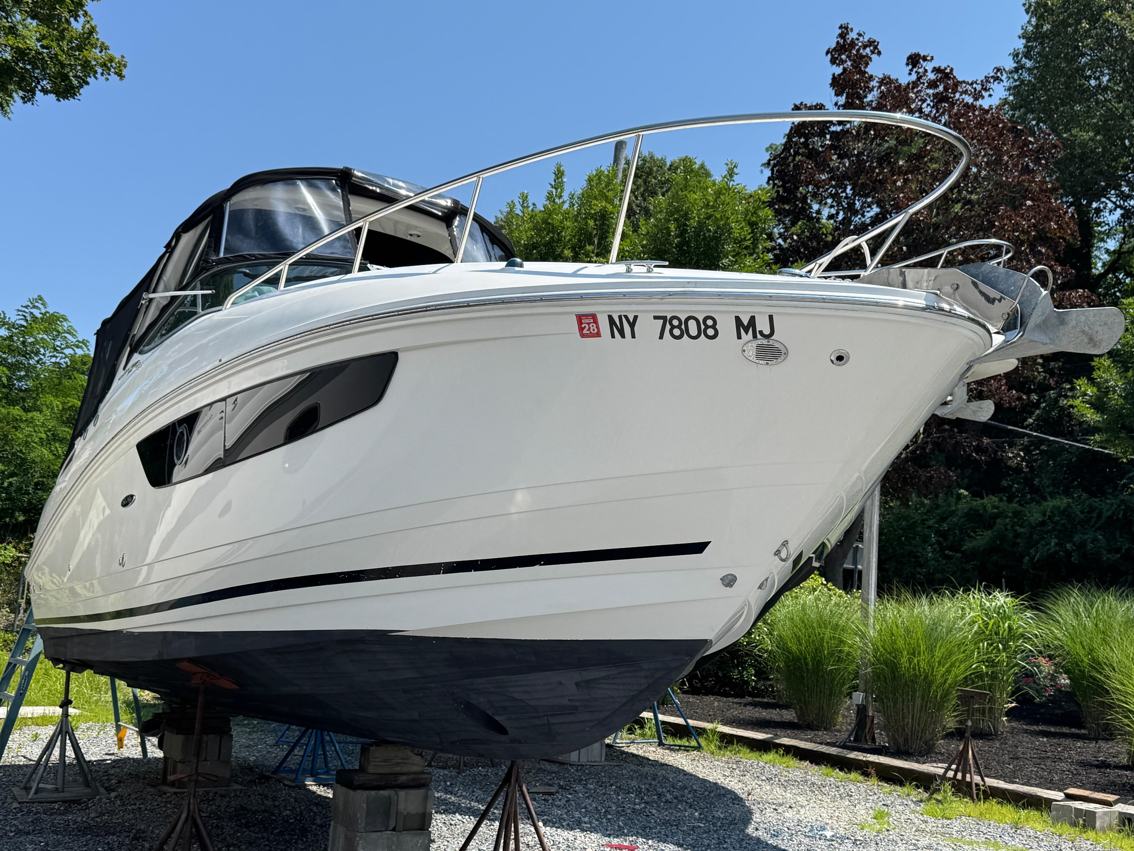 2014 Sea Ray 280 Sundancer boat on stands, surrounded by greenery.
