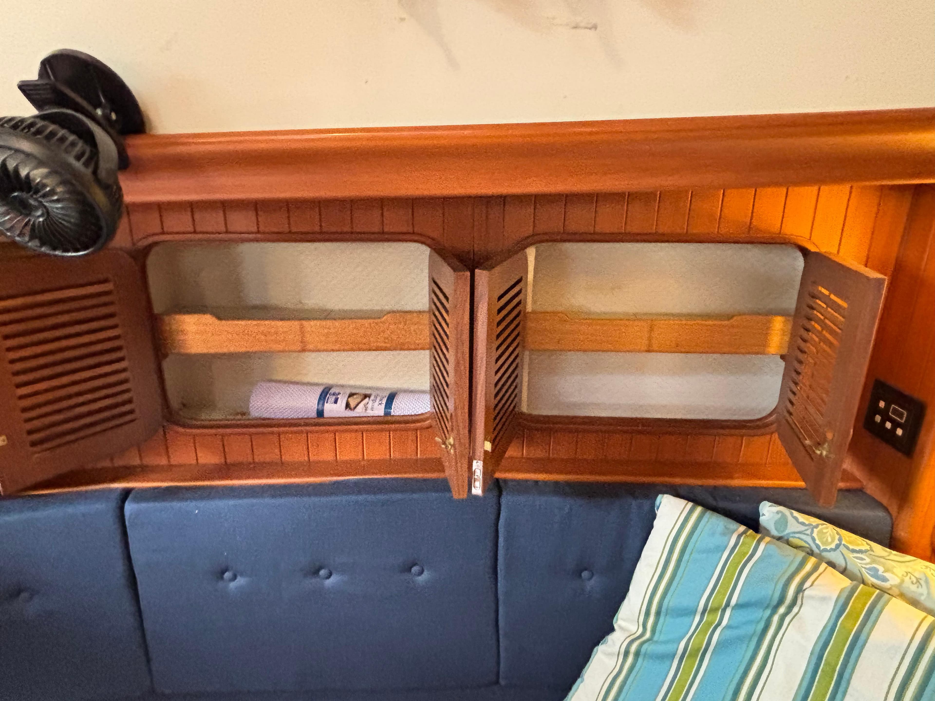 Wooden cabinet with open doors, blue cushions, and striped pillows on a 1987 Ta Shing Tashiba 36.