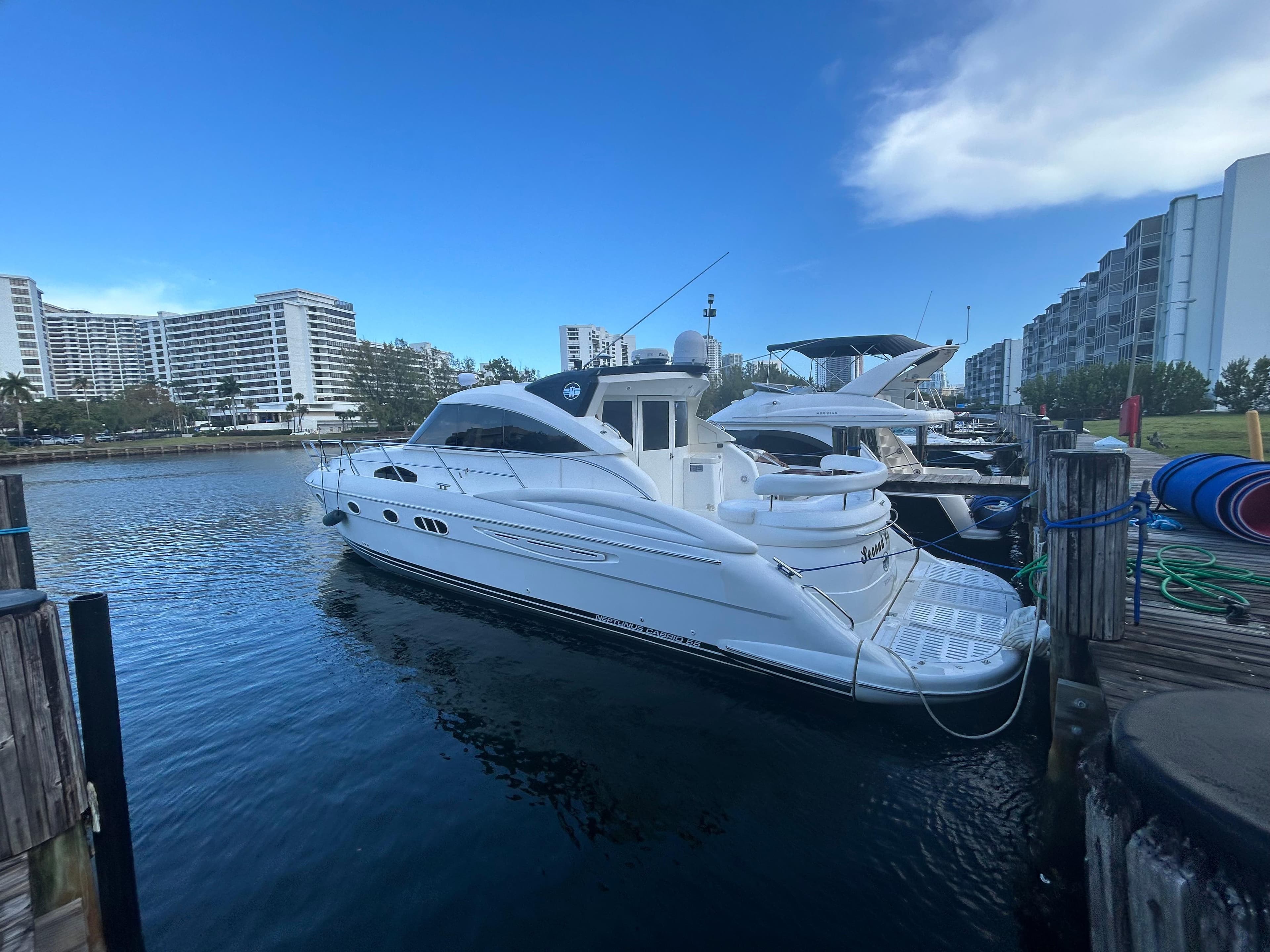 Luxury 2006 Neptunus 55 Cabrio yacht docked in a marina with modern buildings.