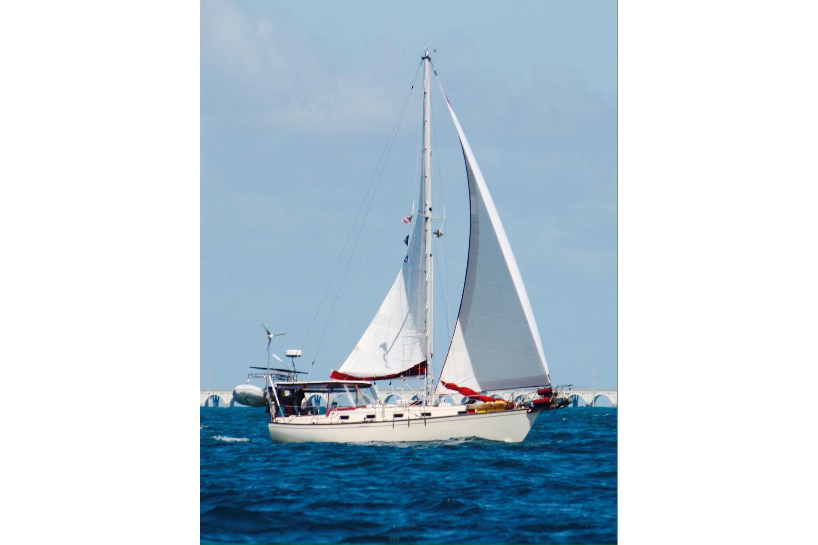 1989 Island Packet 35 sailboat navigating blue ocean waters under clear skies.