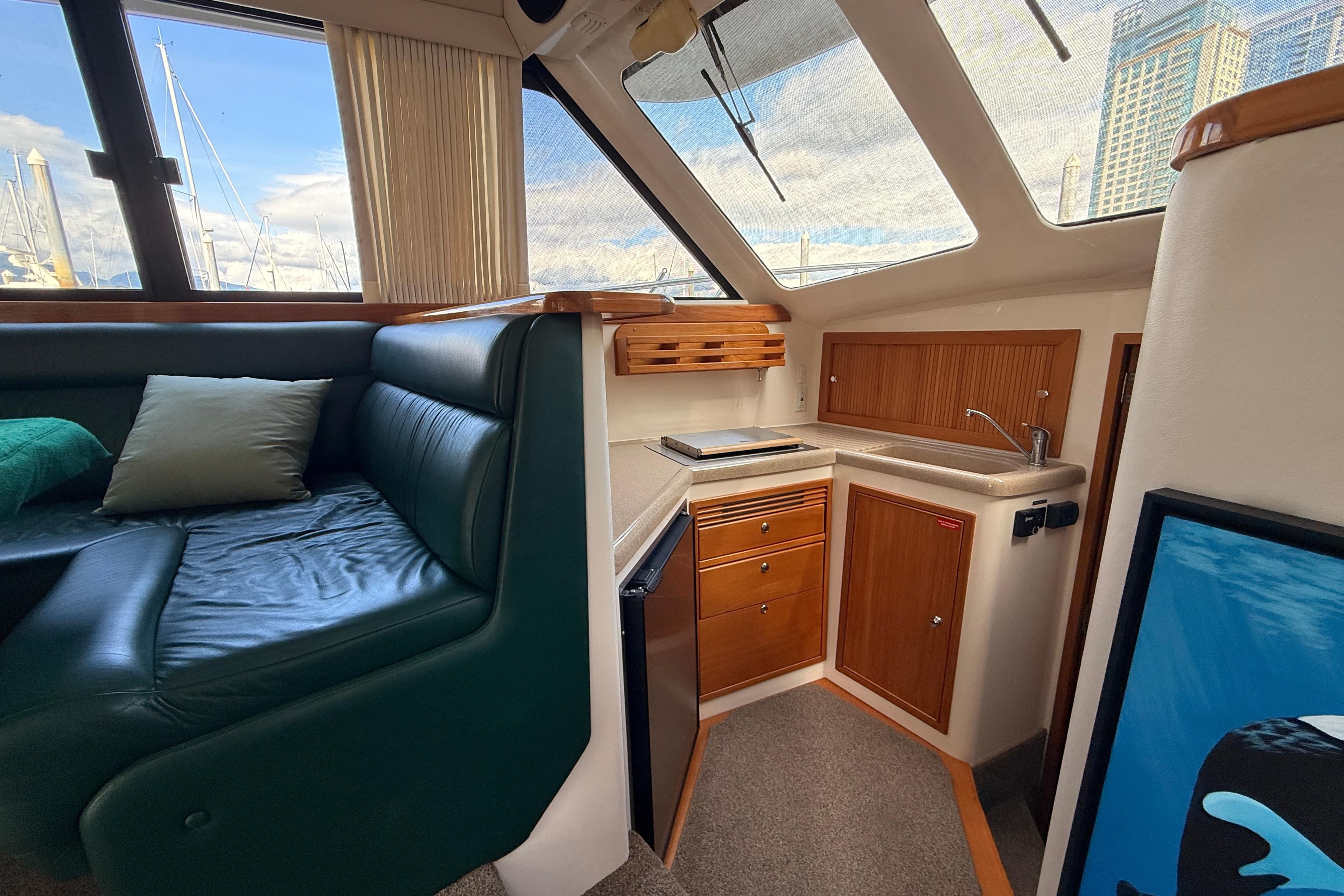 Interior of 1999 Riviera 34 Convertible yacht with cozy seating and compact kitchen area.