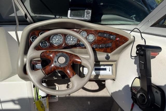 Steering wheel and dashboard of a 2000 Crownline 205 CCR boat.