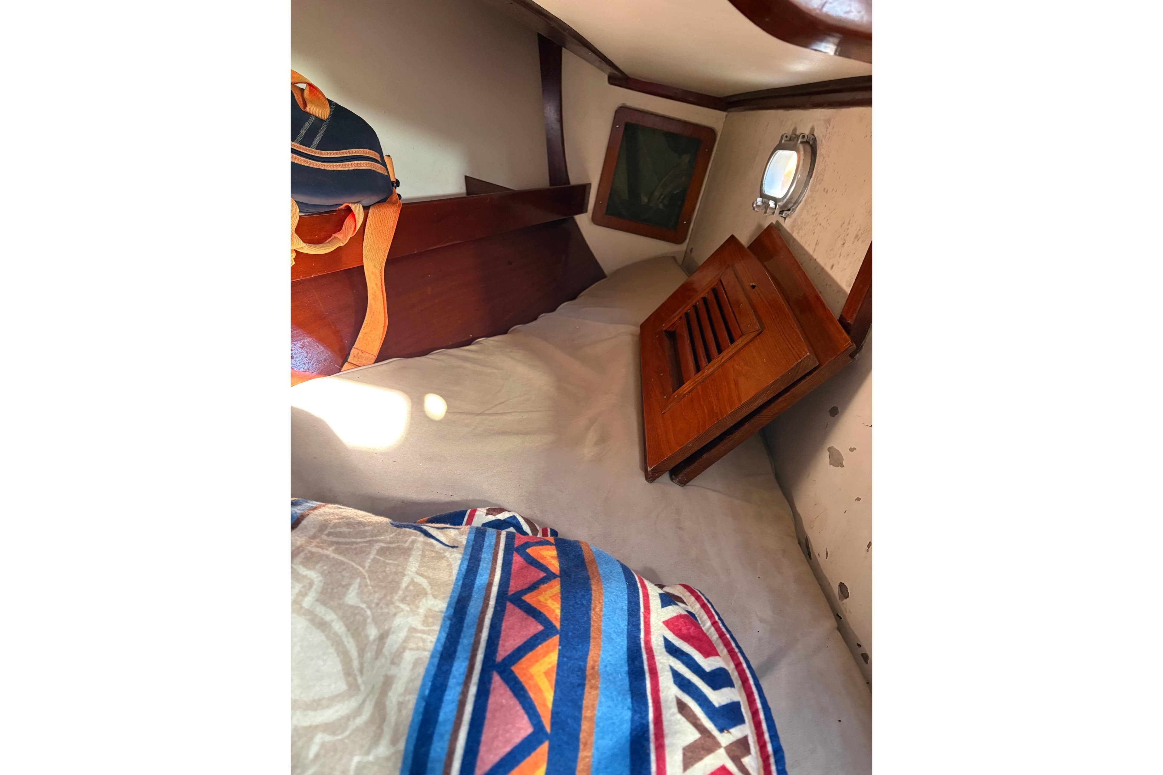 Cozy cabin interior of 1973 Carter 33 sailboat with colorful bedding and wooden accents.