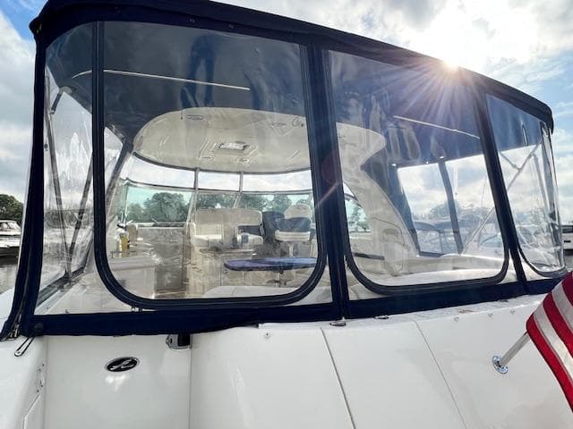 2005 Sea Ray 500 Sundancer yacht with enclosed cockpit, American flag, and sunlit sky.