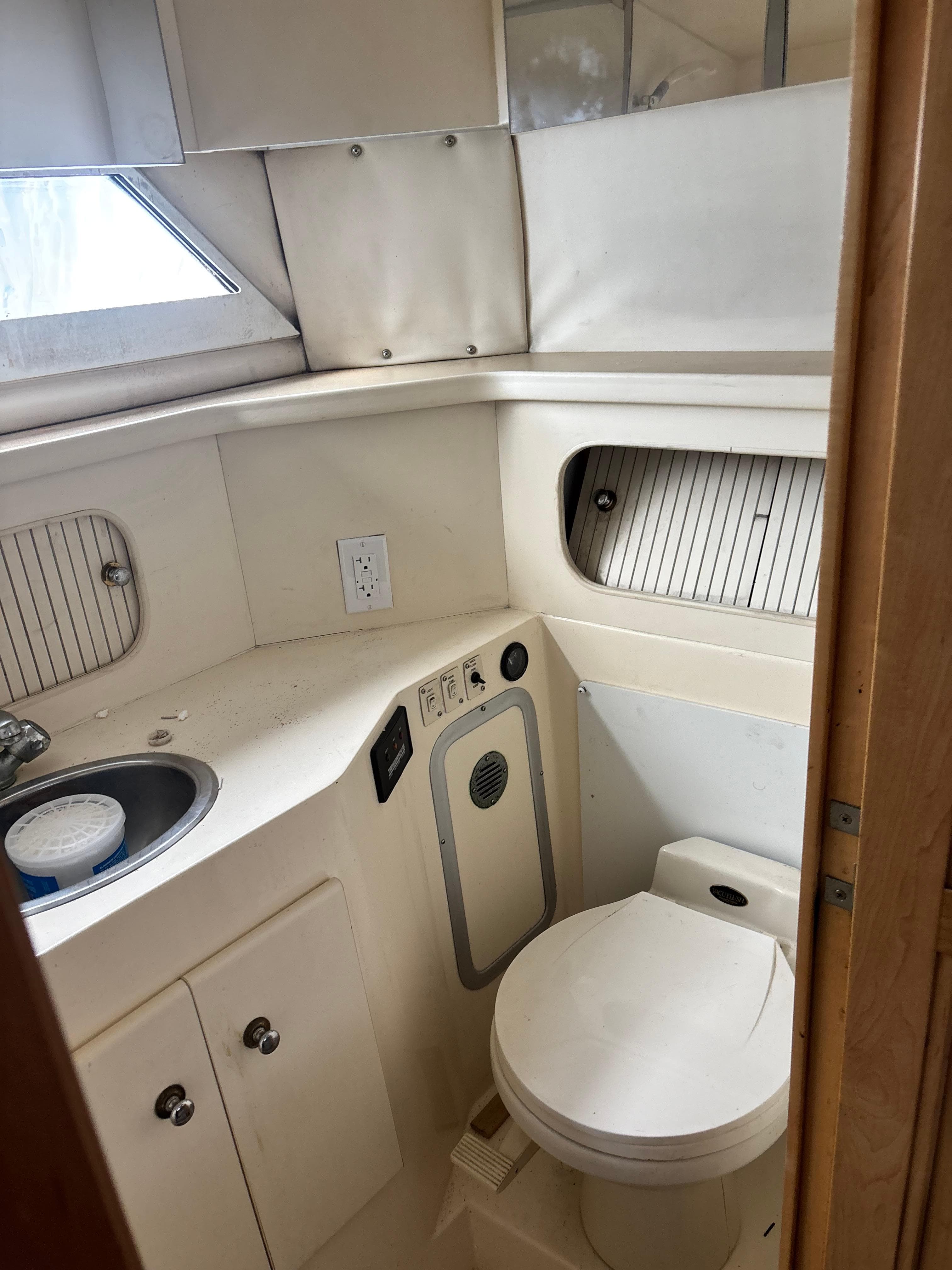 1997 Carver 405 yacht bathroom with toilet, sink, and storage cabinets.