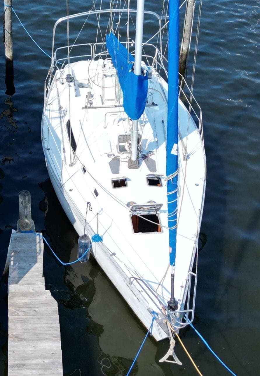 1987 Hunter 34 sailboat docked, featuring white hull and blue sail cover.