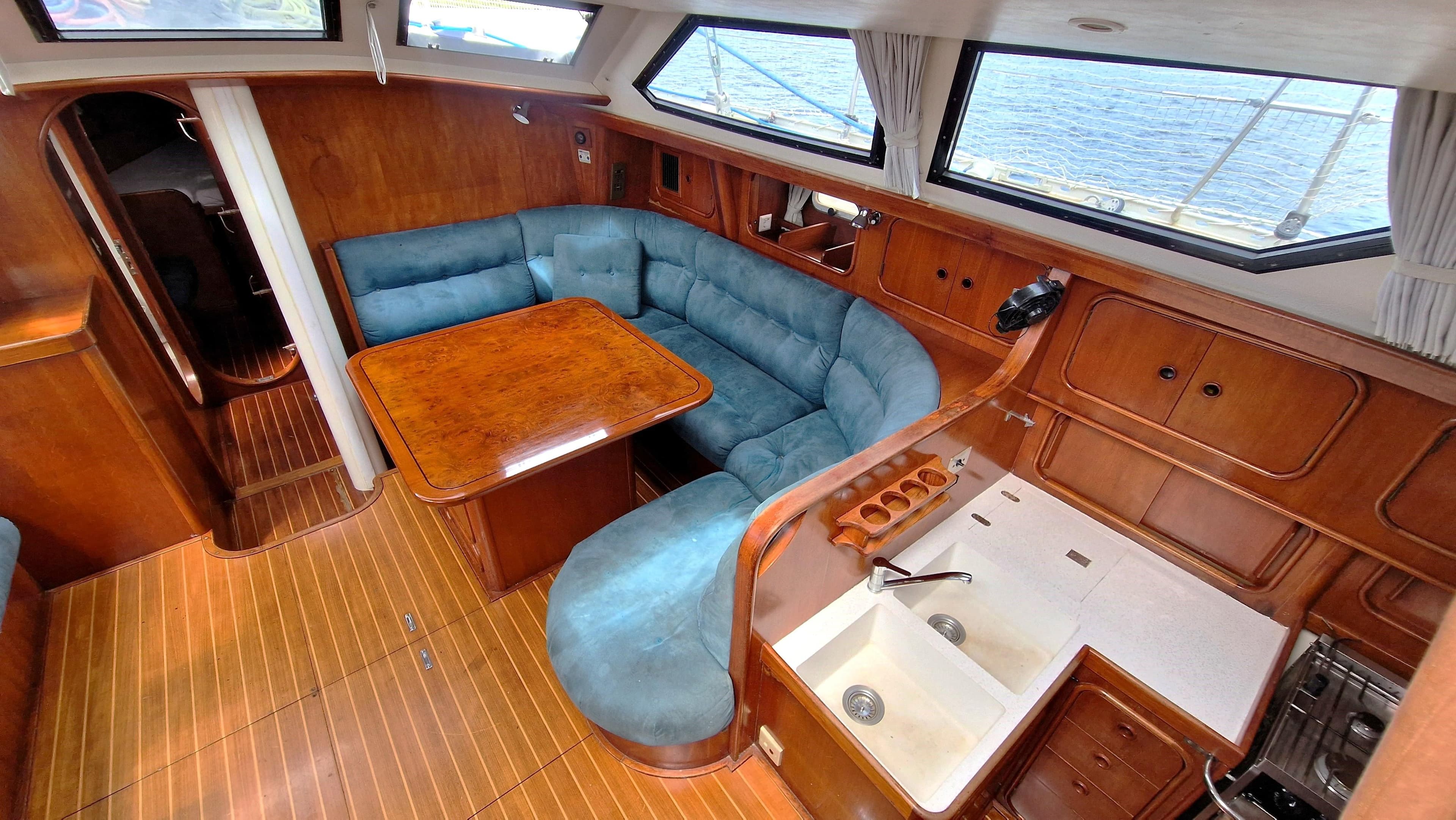 Luxurious 1995 Oyster 55 yacht interior with wood finish, blue seating, and spacious kitchen area.
