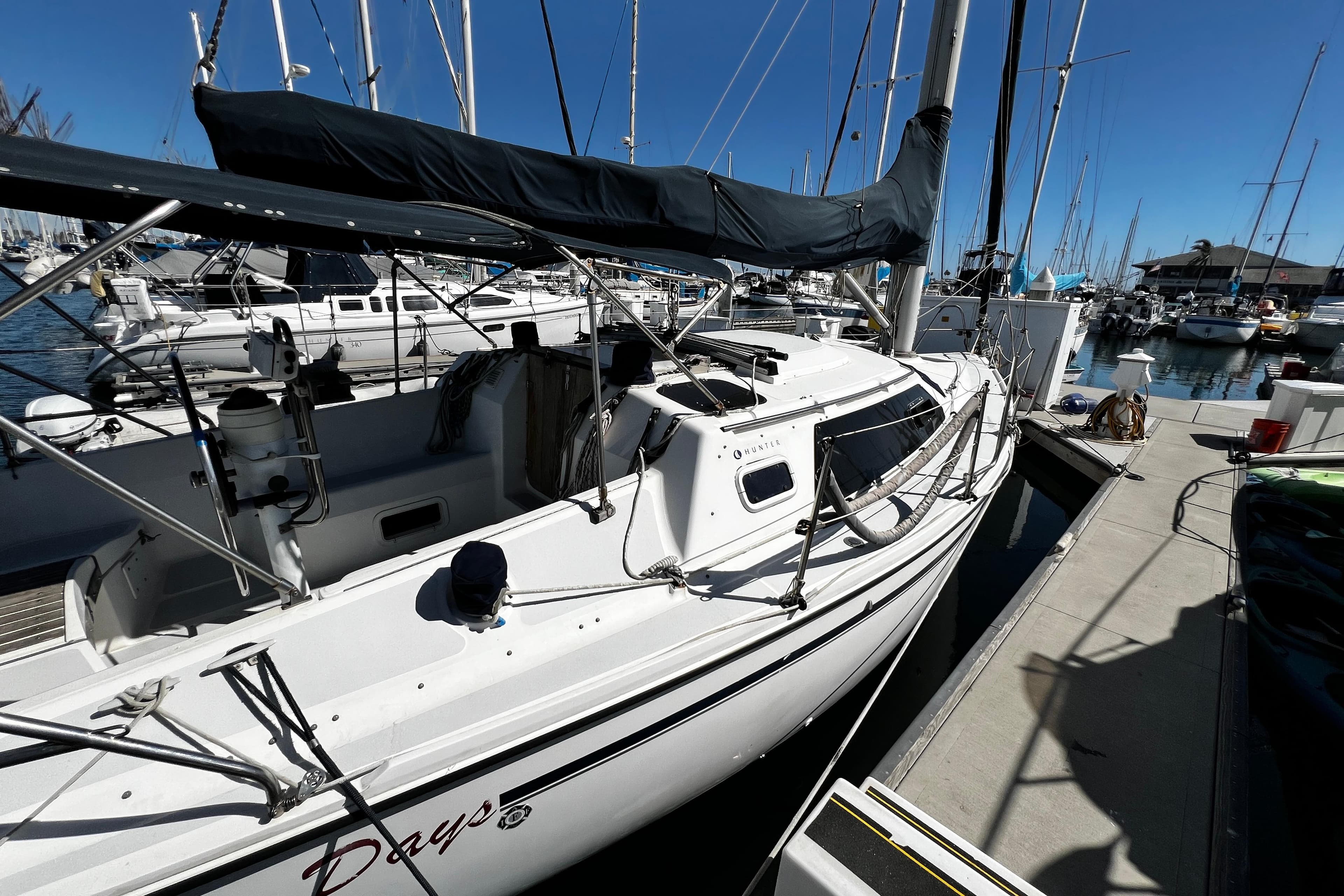 1989 Hunter Vision 32 sailboat docked at marina, surrounded by other boats under clear blue sky.
