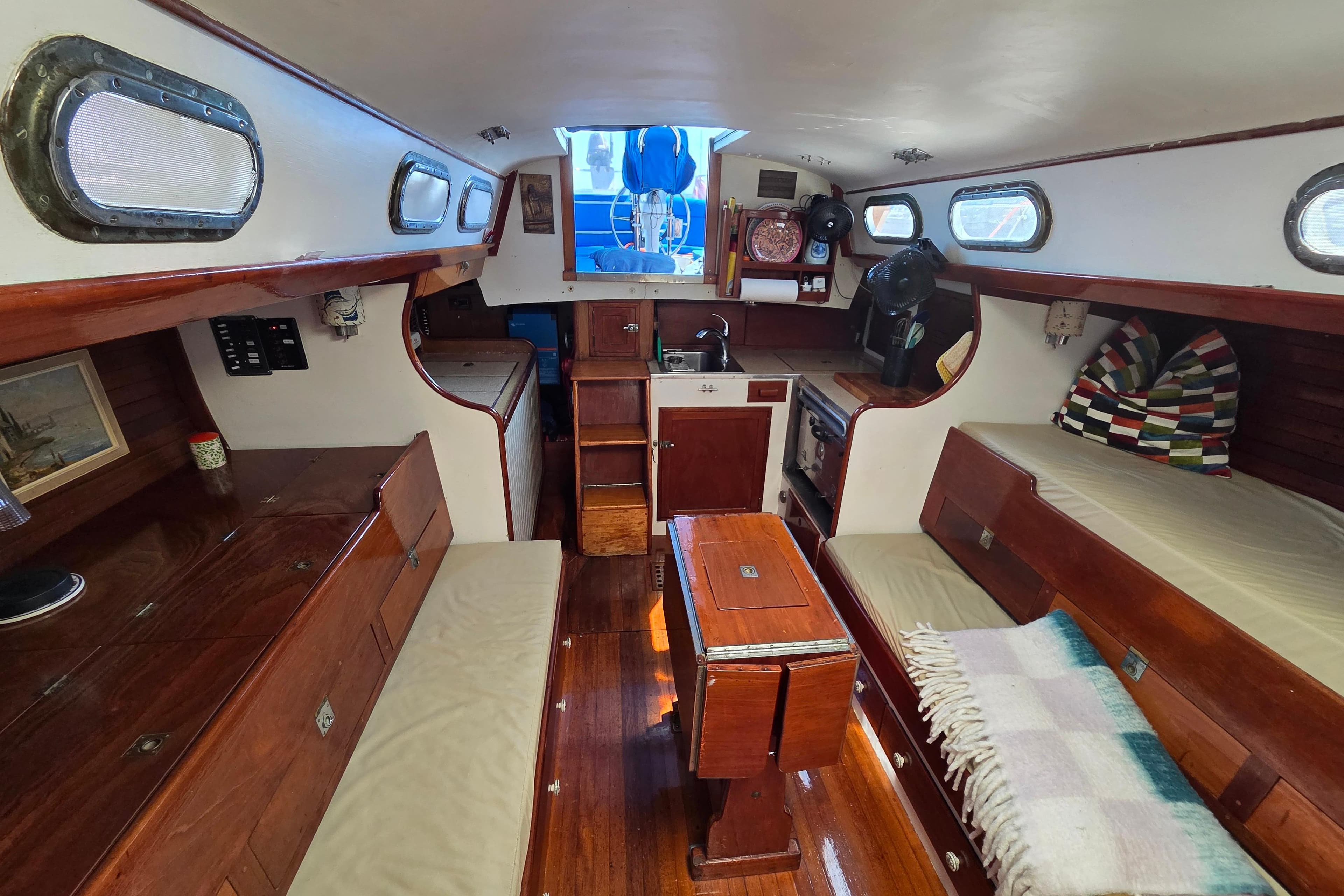 Interior of a 1961 Hinckley Bermuda 40 sailboat with wooden furnishings and cozy seating.