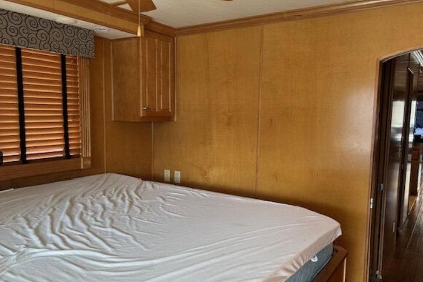 Bedroom interior of 2007 Sumerset Lakeview HD houseboat with wooden walls and blinds.