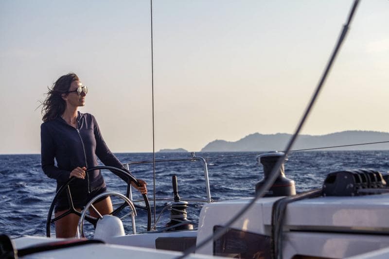 Woman steering Jeanneau Sun Odyssey 410 sailboat on open sea, 2026 model.