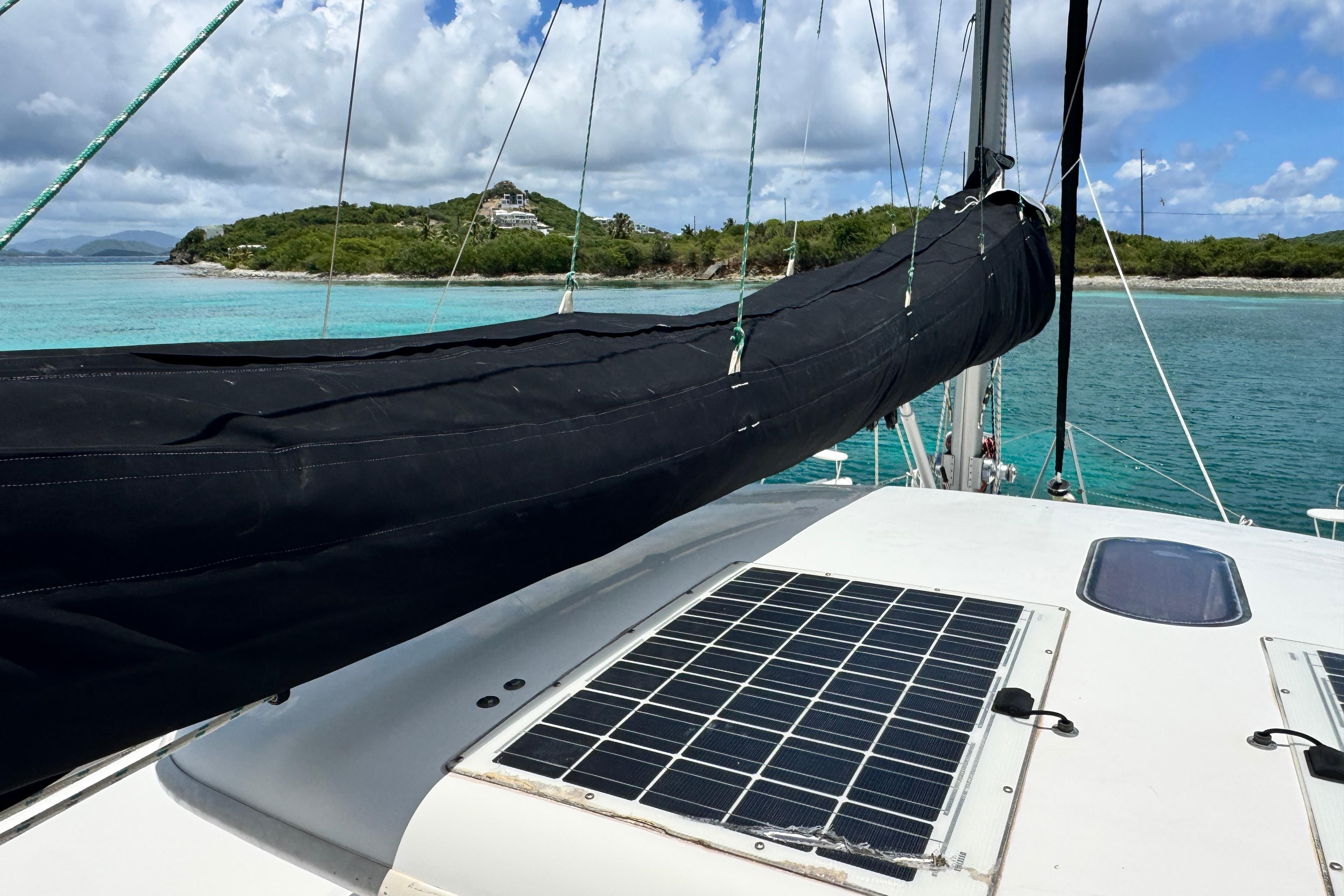 Sailboat deck with solar panel, Leopard 46 model, cruising near tropical island waters.