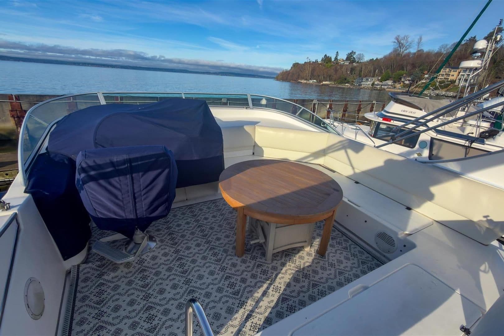 2002 Bayliner 3988 Command Bridge Motoryacht deck with seating and table, overlooking serene waters.