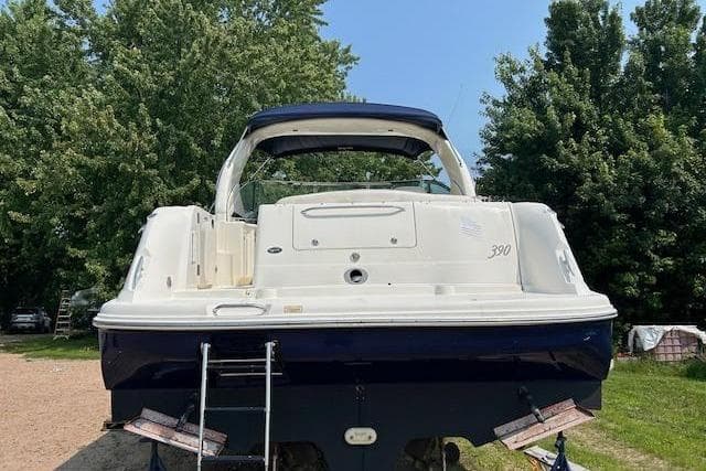2005 Sea Ray 390 Sundancer yacht, rear view, parked on land with trees in background.