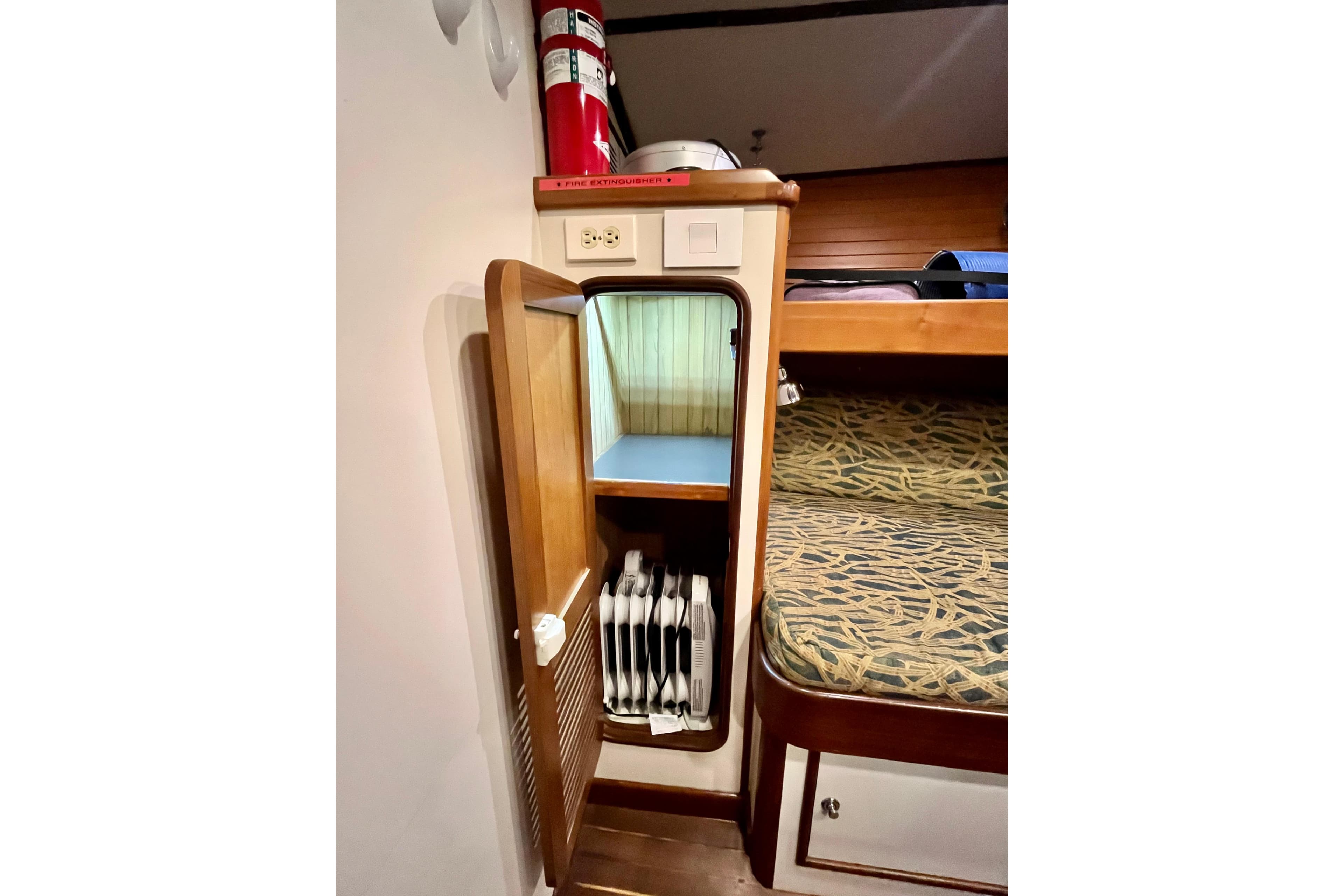 1996 Nordhavn 46 interior with open wooden cabinet, fire extinguisher, and patterned bunk bed.