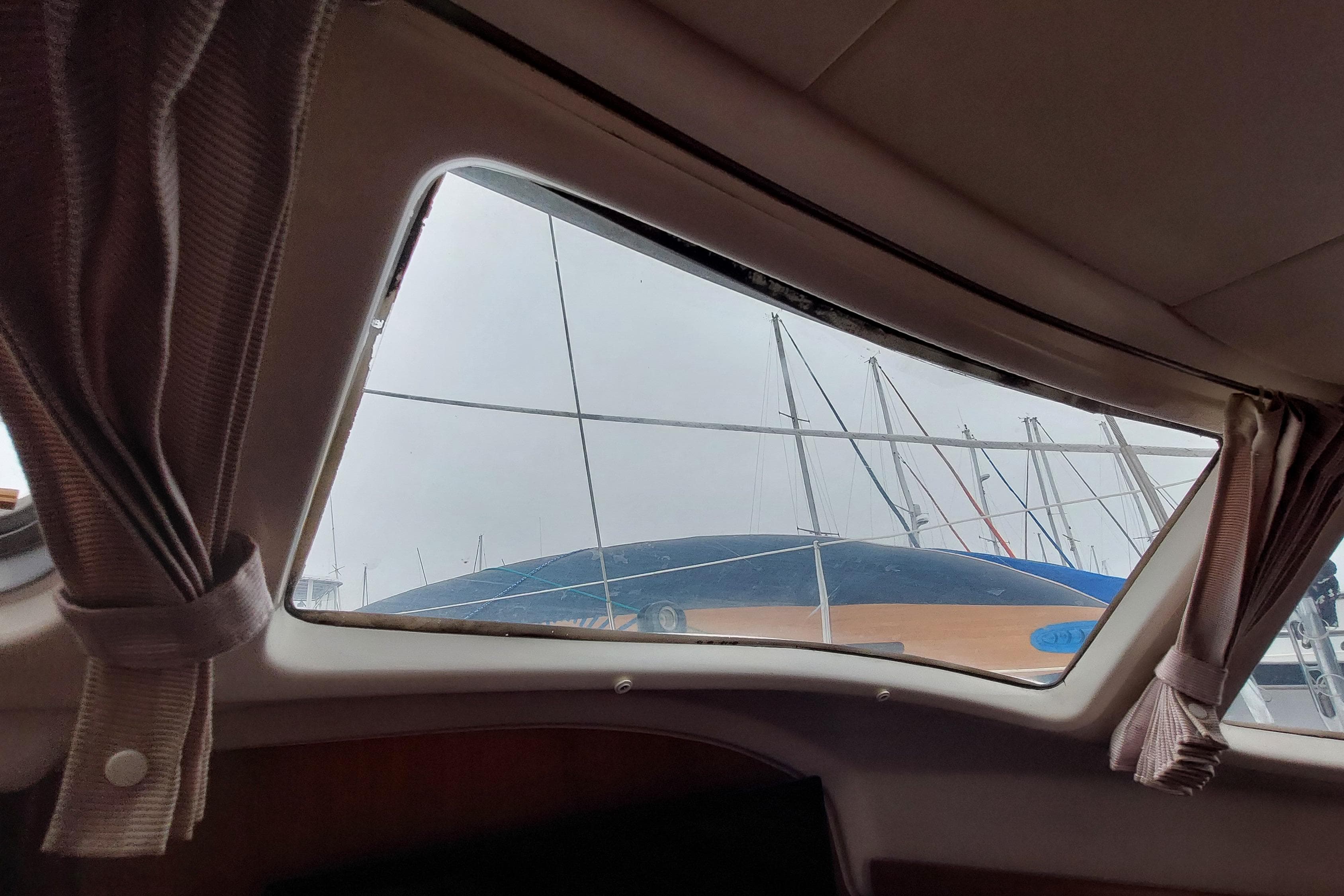 Interior view from Jeanneau Sun Odyssey 43 DS, showing marina and sailboat masts outside.