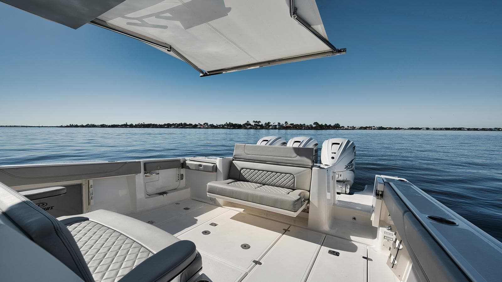 Luxury 2022 Pursuit S-378 boat interior with seating, ocean view, and clear blue sky.