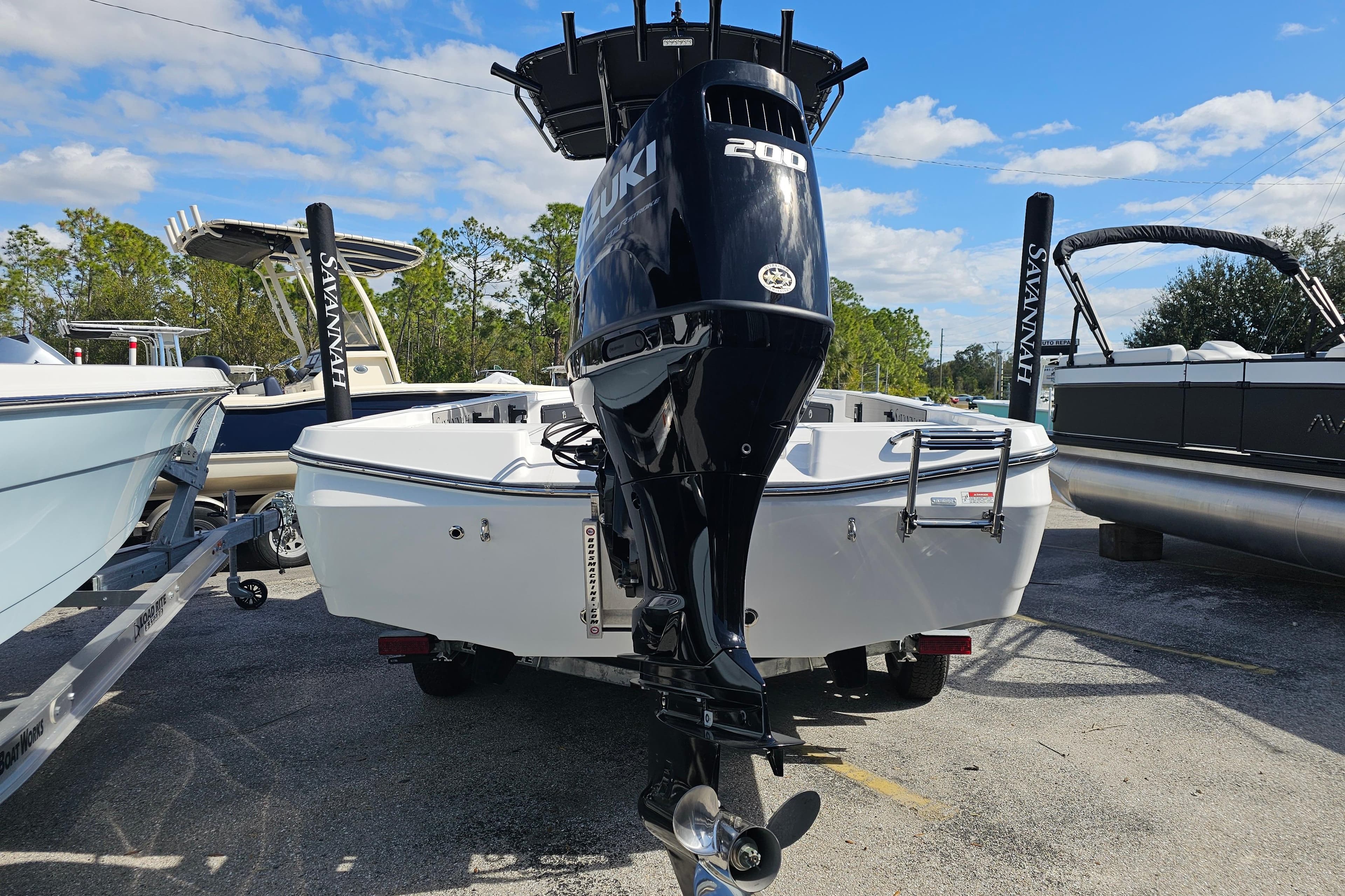 2025 Savannah 220 IS boat with Suzuki 200 engine, parked outdoors under blue sky.