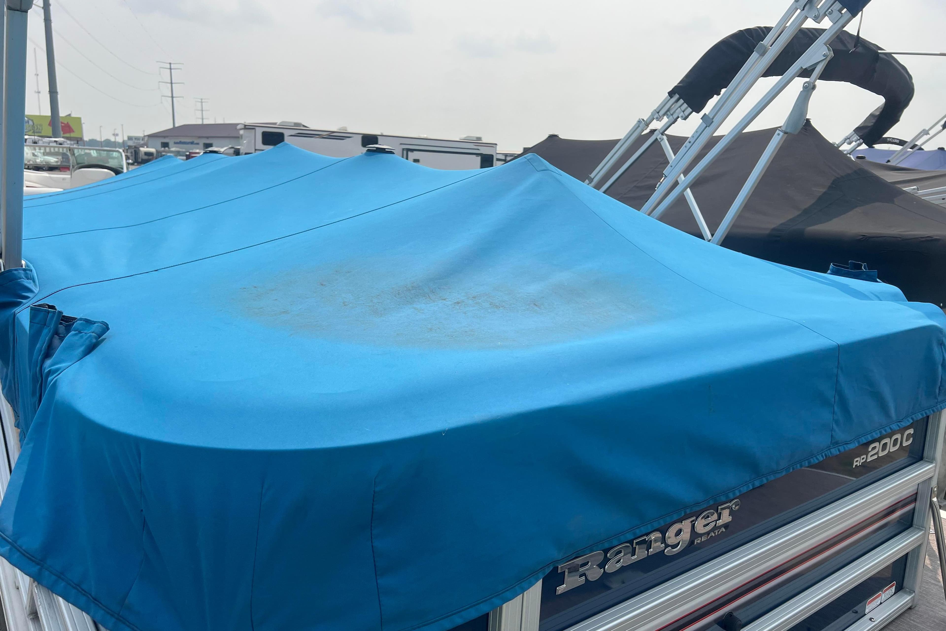 2019 Ranger Reata 200C boat with blue cover in a marina setting.