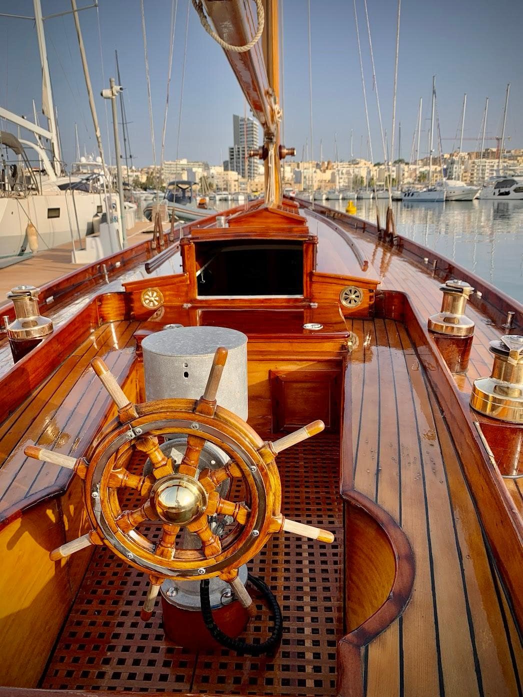 Vintage 1940 William Fife Bermudan Cutter with wooden deck and helm, docked in a marina.